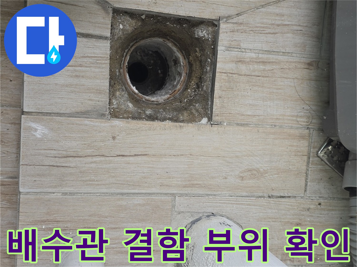 노출된 배수구 파손부와 주변 타일 마감 상태를 촬영한 사진입니다.