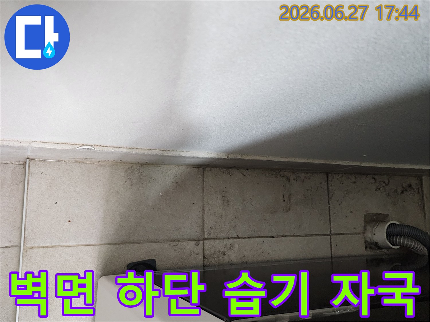 세탁실-벽면-하단에-지속적인-수분-노출로-인해-타일-변색과-곰팡이가-발생한-누수-현장의-모습입니다.