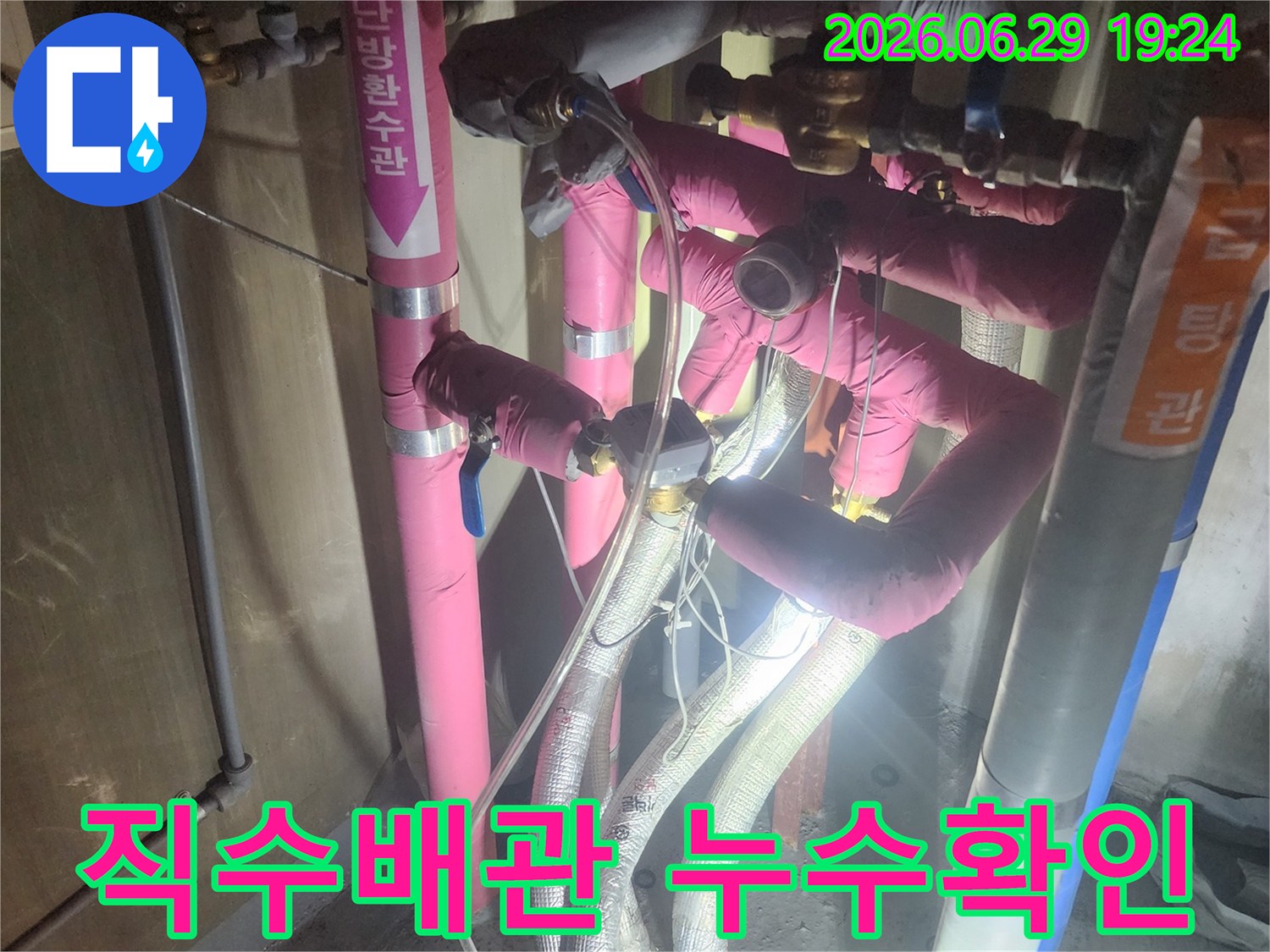 분홍색과 회색 단열재로 덮인-배관들이 복잡하게 얽혀있고-압력 게이지가 연결된-누수 테스트 현장입니다