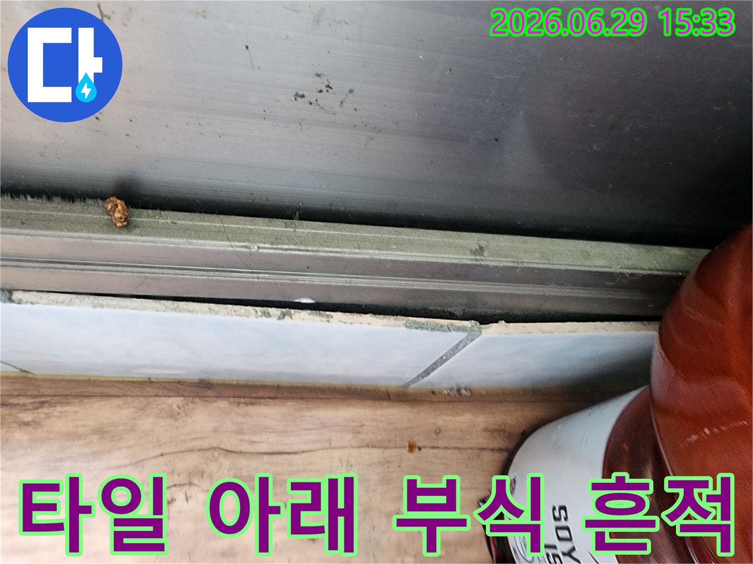 시흥 대림아파트 누수 현장에서-타일 아래로 물기가 침투하여 발생한 부식 흔적을 상세히 보여주는 사진입니다