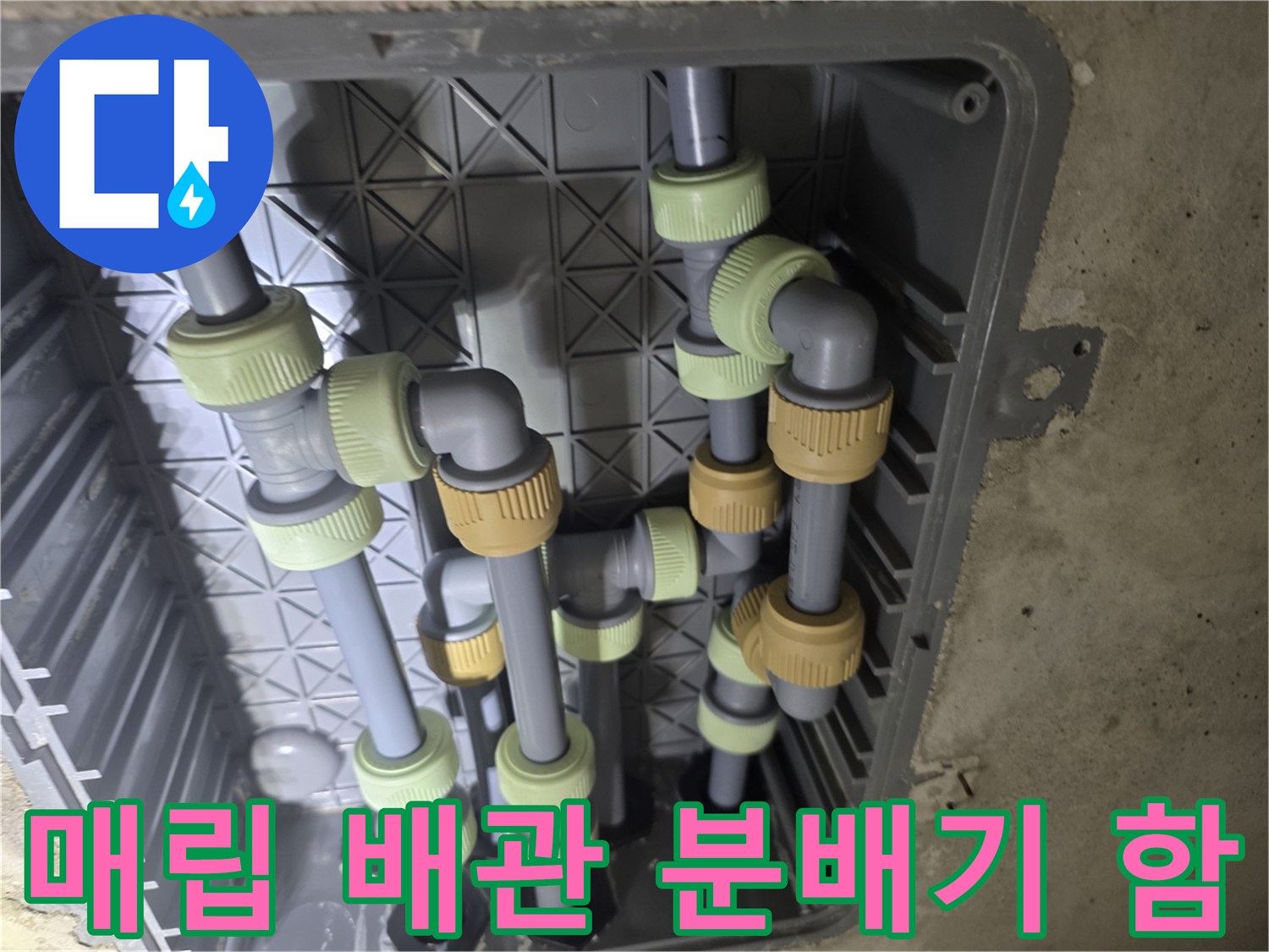 화장실 벽면에 위치한 배관 분배기 함 내부의 복잡한 배관 구조를 보여줍니다.