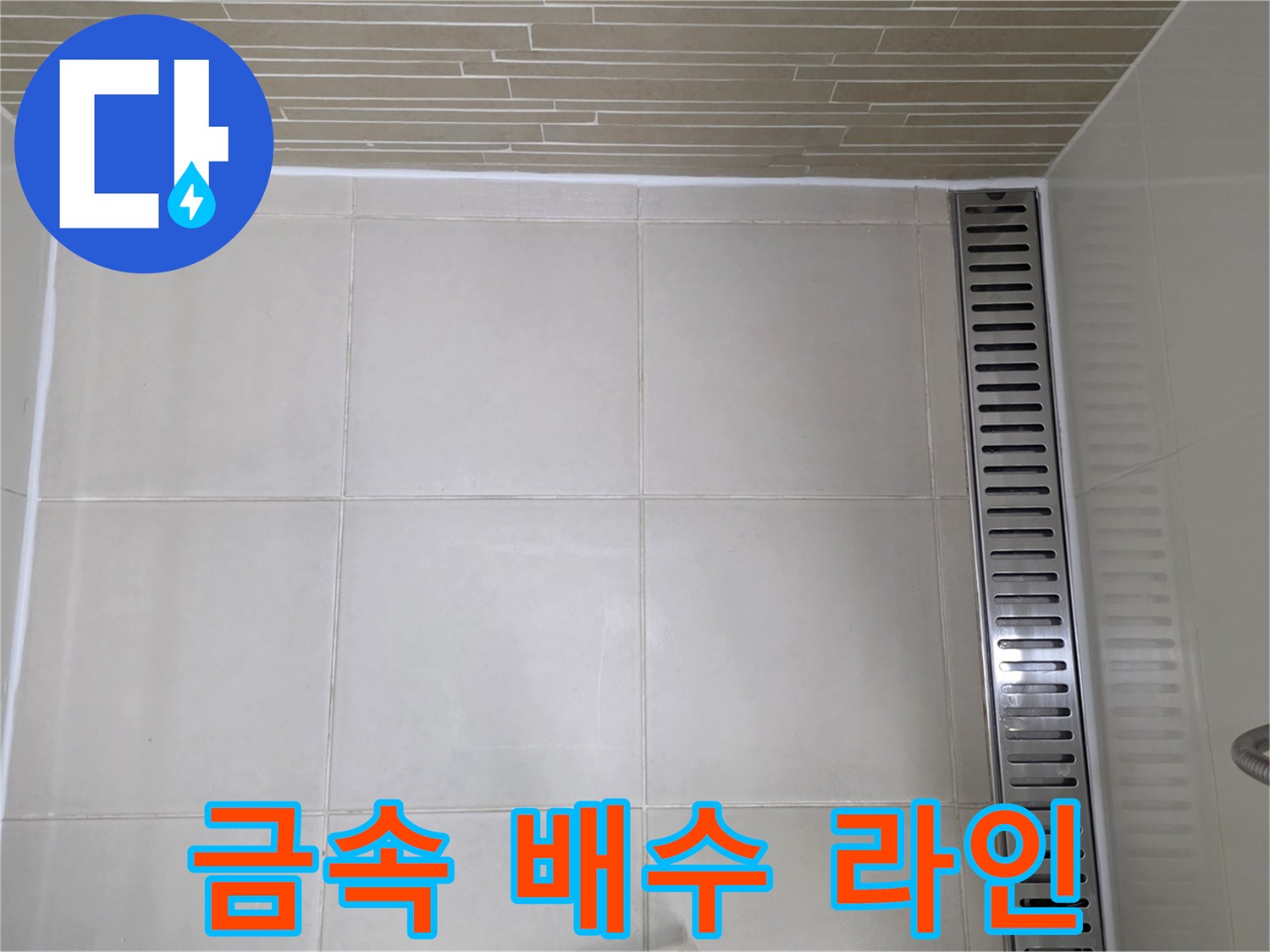 바닥 타일과 일직선으로 배치된 스테인리스 배수 트렌치 근접샷