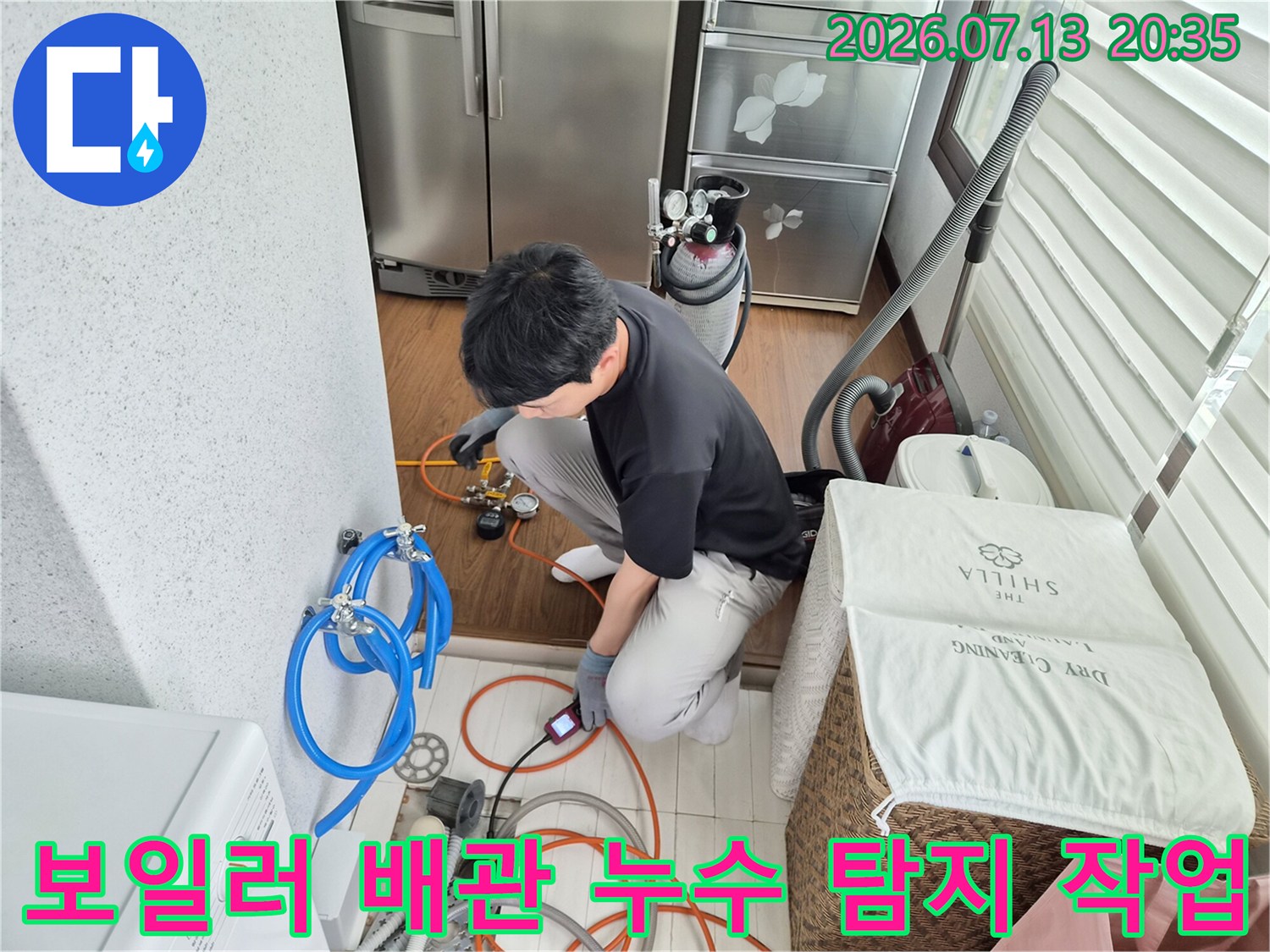 보일러 아래 위치한 배관에 장비를 연결하여 압력 손실 여부를 확인하는 전문 기술자의 모습