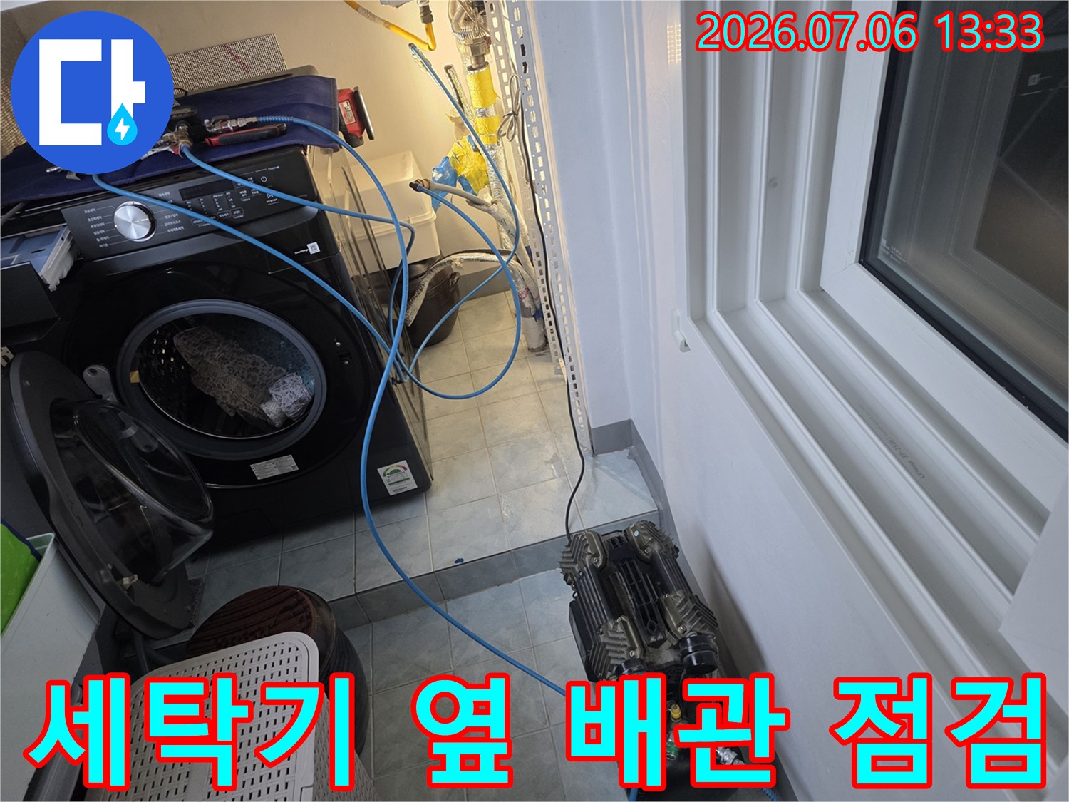 세탁기 옆에 설치된 노출 배관과 바닥면의 누수 확인을 위한 장비가 배치된 모습
