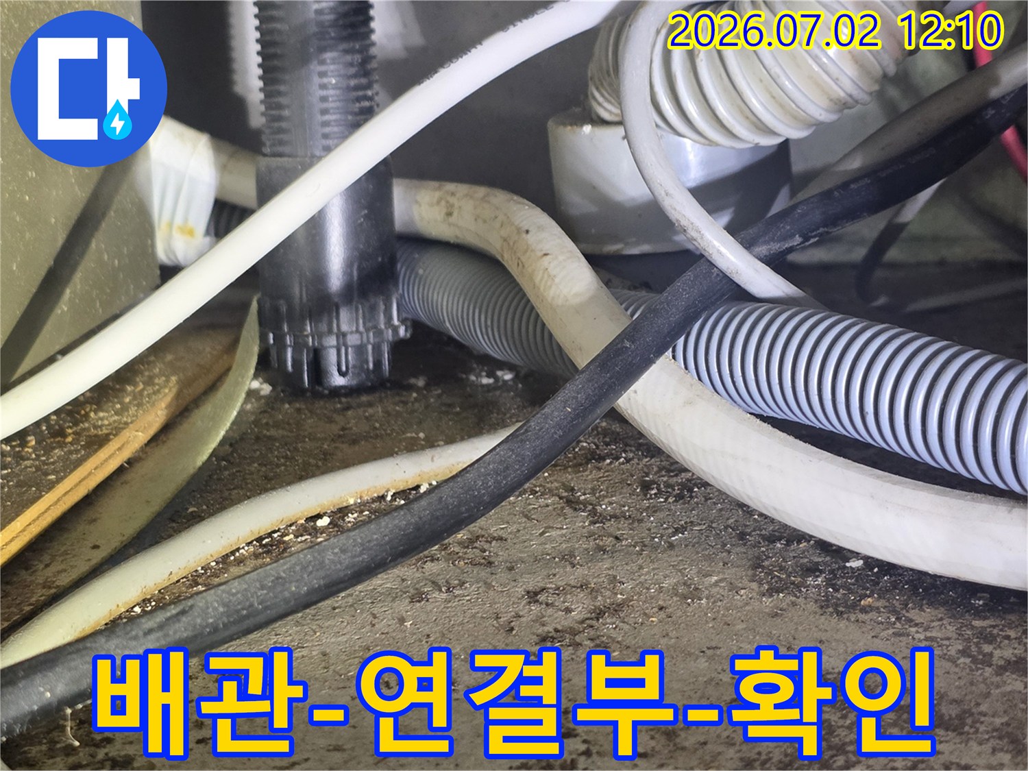 이 사진은-다양한 배관과-전선이 얽힌-공간에서-누수 여부를-확인하는-장면을 보여줍니다.