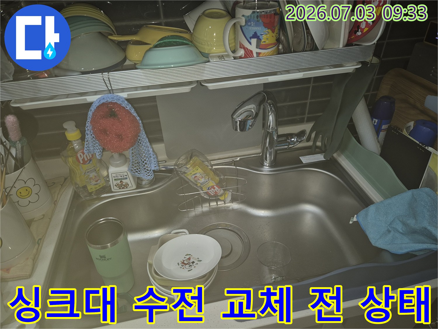 세제와 수건이 놓인 싱크대 공간에 위치한 기존 수전