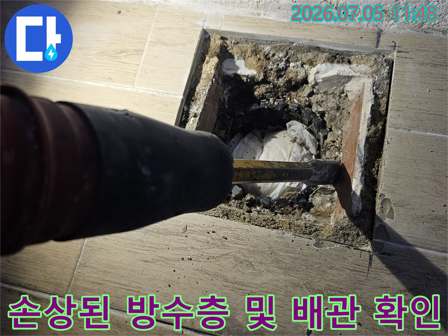 파내어진 타일 사이로 드러난 노출 배관과 주변의 파손된 방수 상태를 촬영한 사진
