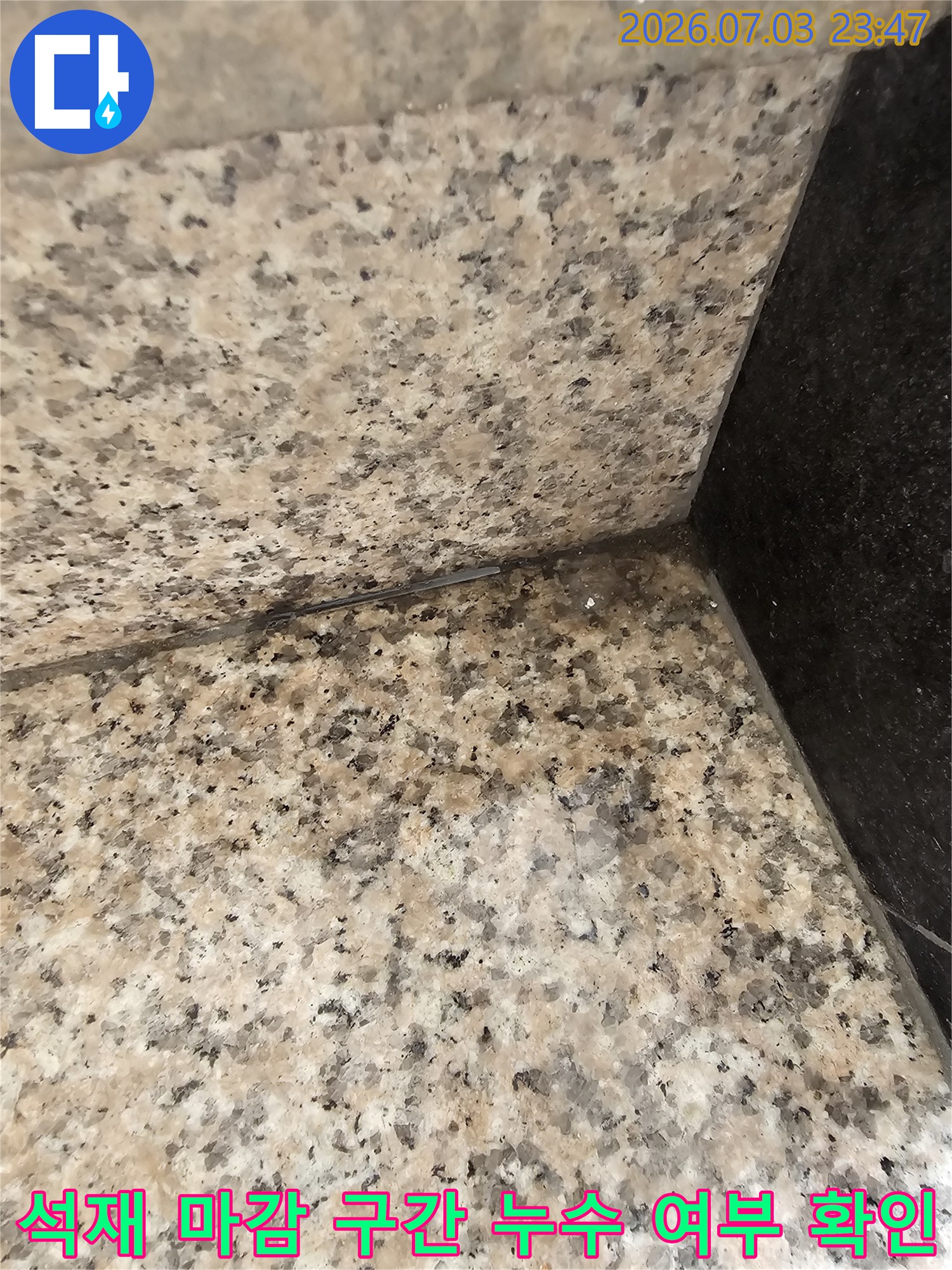 상가 건물 지하 입구의 석재 바닥과 벽체 접합 부위를 촬영한 현장 점검용 사진입니다.