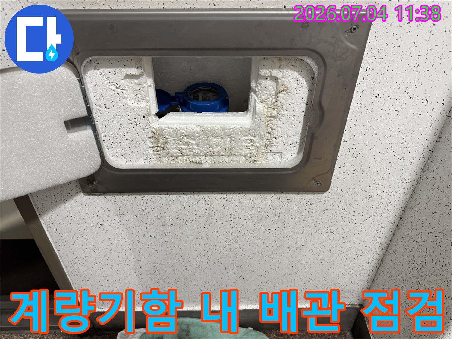 흰색 보호 덮개와 단열재로 감싸진 계량기 함 내부의 수도 배관.