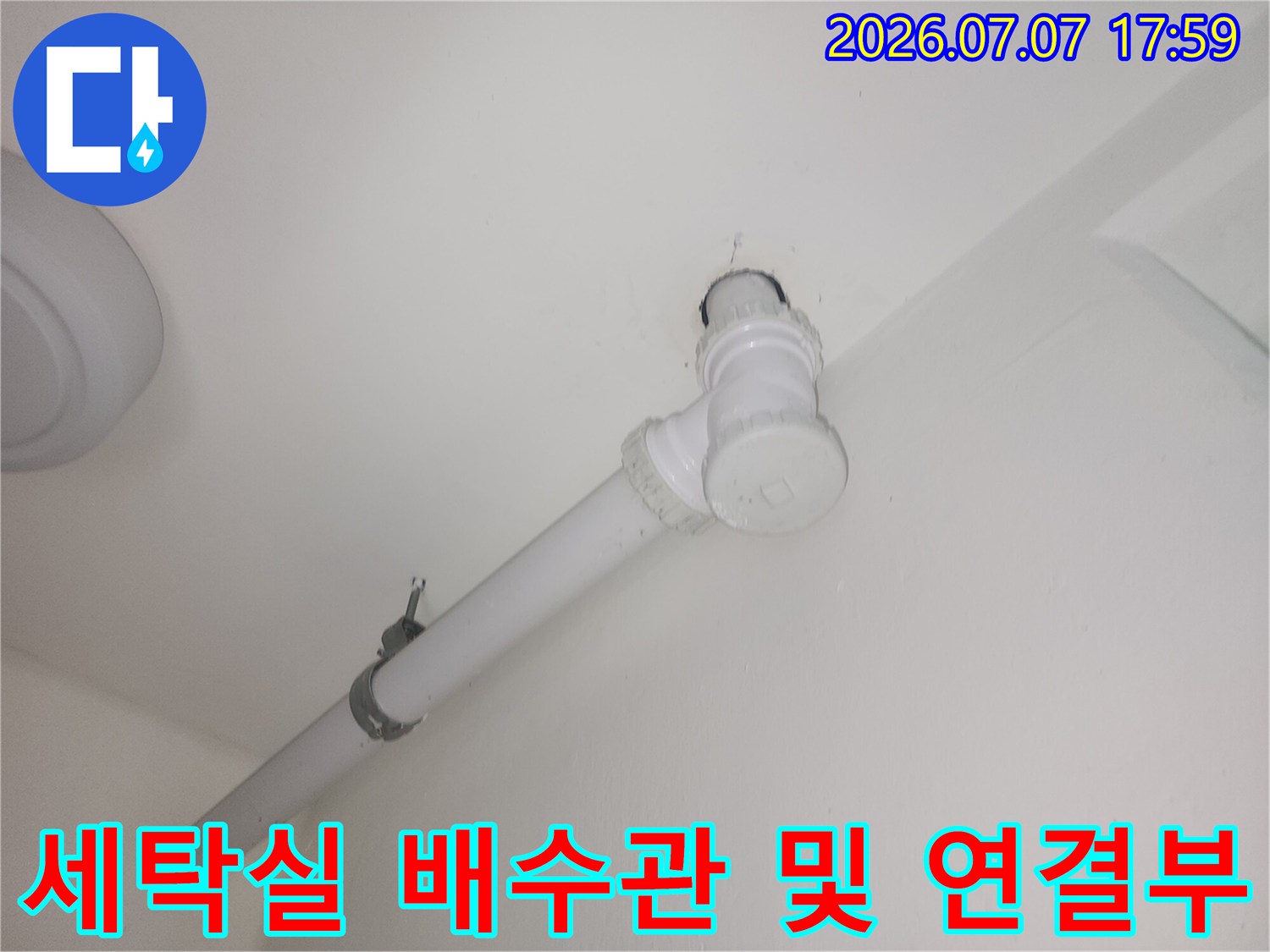하얀색 벽면과 천장에 고정된 세탁실 하수 배관 노출 구간