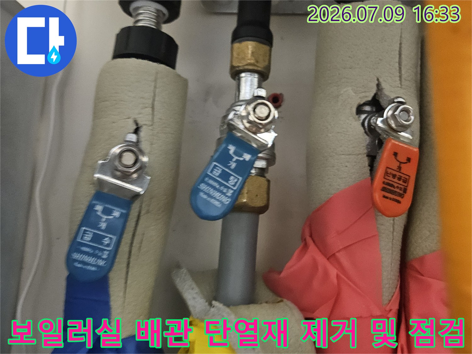 보일러실 내 온수와 냉수 배관의 단열재를 제거하고 연결 부위를 점검하는 모습