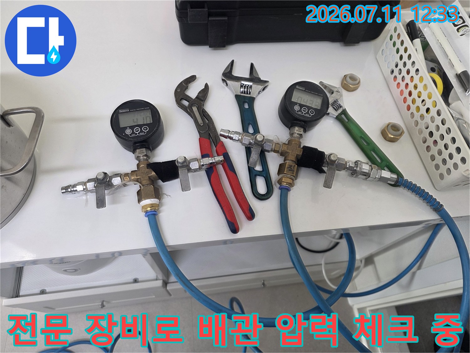두 개의 게이지와 파란색 호스가 연결된 공압 점검기 세팅 모습
