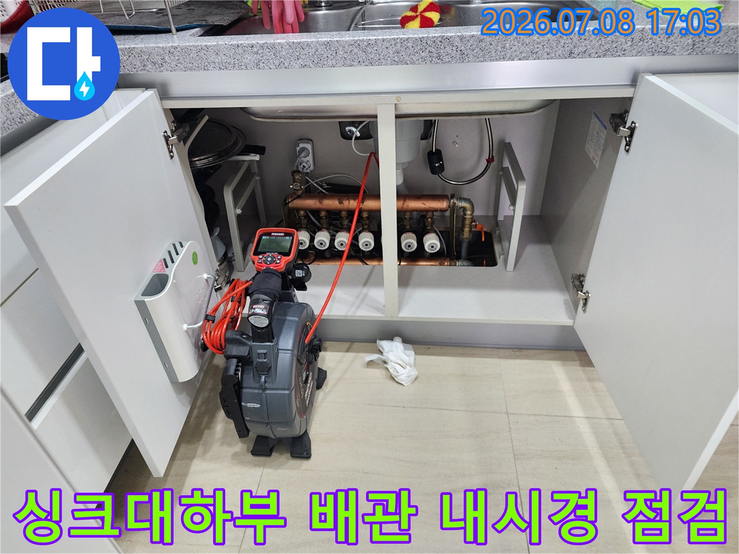 싱크대 하단부를 열고 내시경 장비를 투입하여 배관 상태를 정밀하게 점검하는 모습