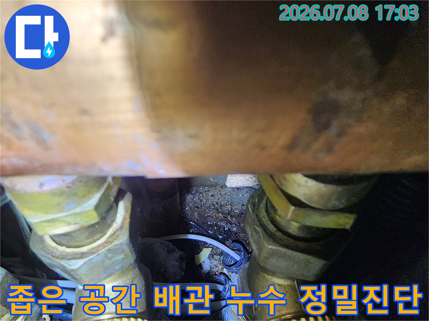 어두운 싱크대 밑면에서 내시경으로 촬영한 배관의 상태를 보여주는 이미지