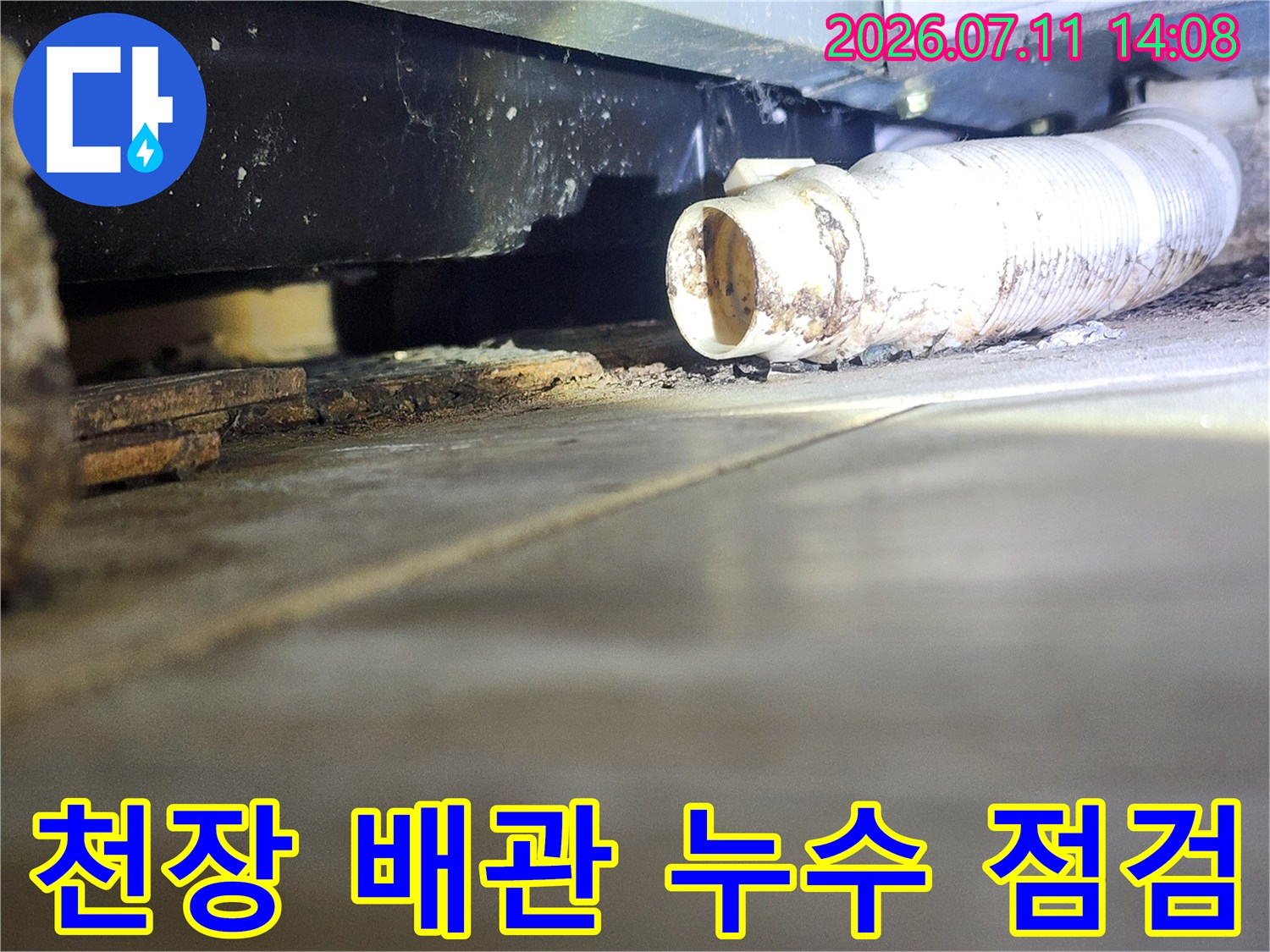 흰색 띠가 둘러진 천장 배관과 습기로 변색된 콘크리트 부위