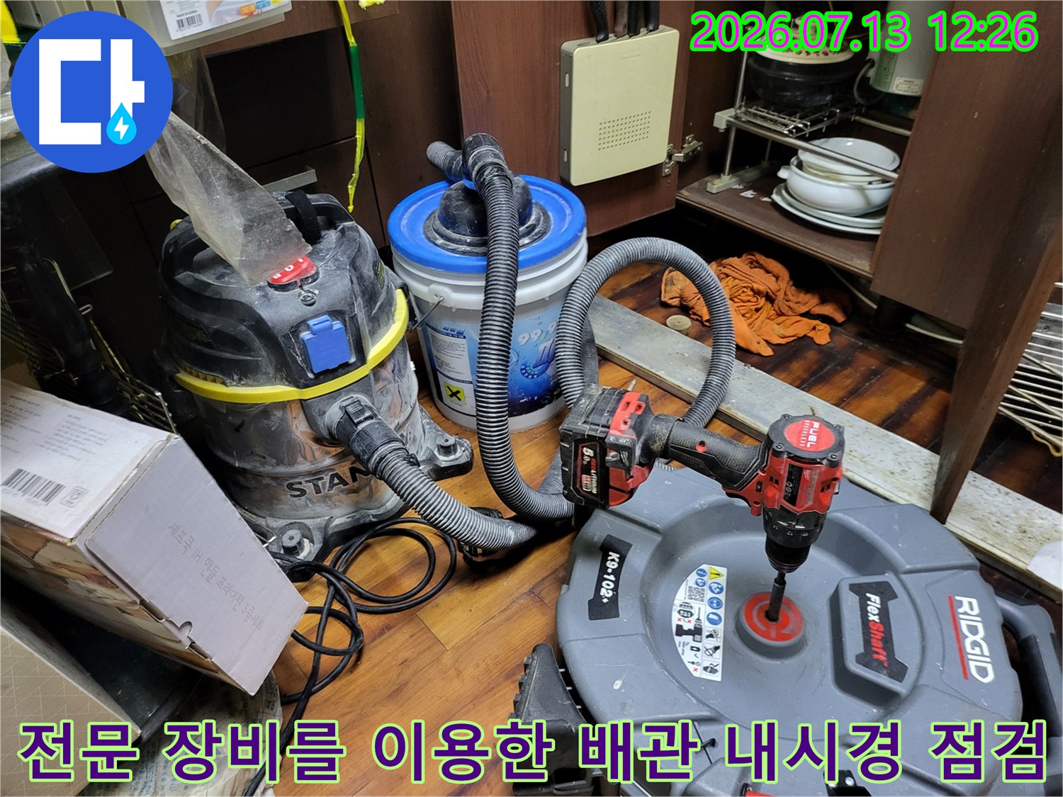 싱크대 하부 공간에서 내시경 카메라와 석션기를 연결해 배수관 내부를 정밀 검사하는 모습