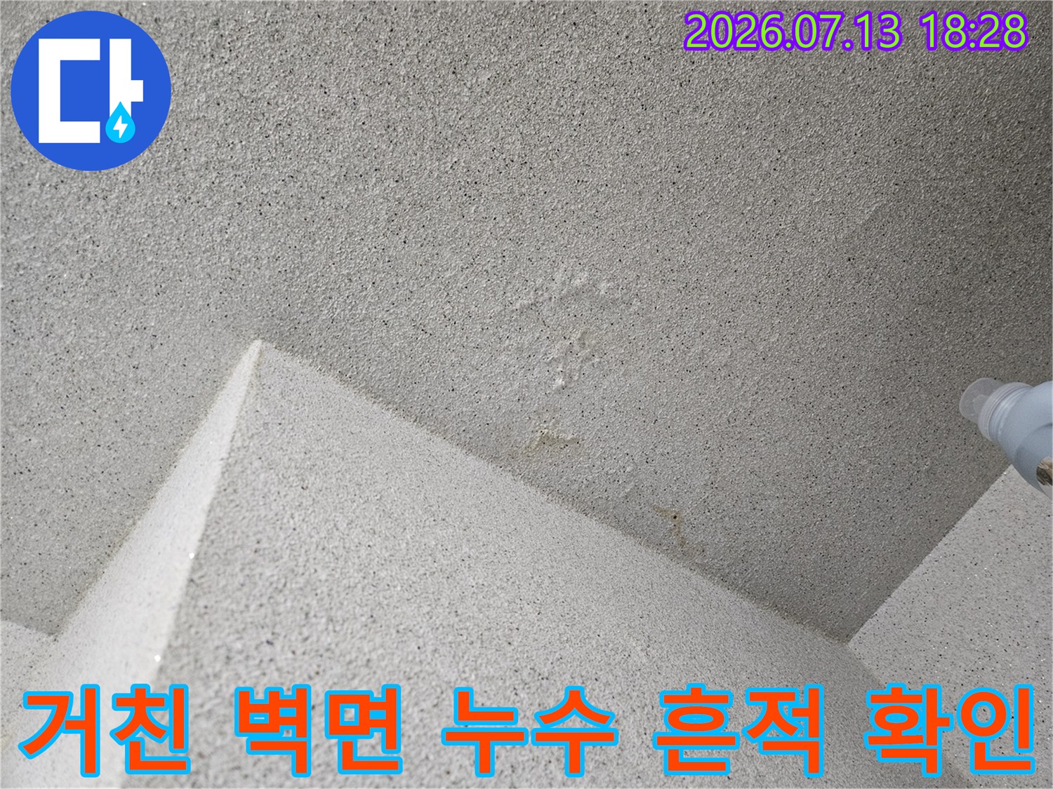거친 질감의 콘크리트 벽체와 배관 연결부 주변의 상태를 촬영한 사진