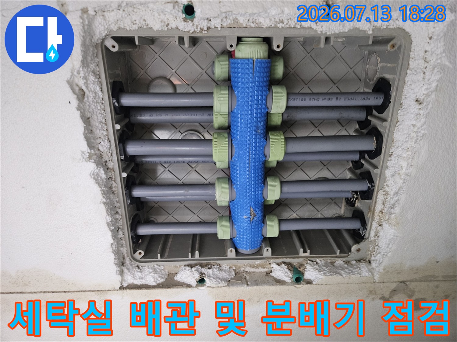 노출된 세탁실 바닥 배관과 파란색 보호재로 감싸진 수직 배관 구조