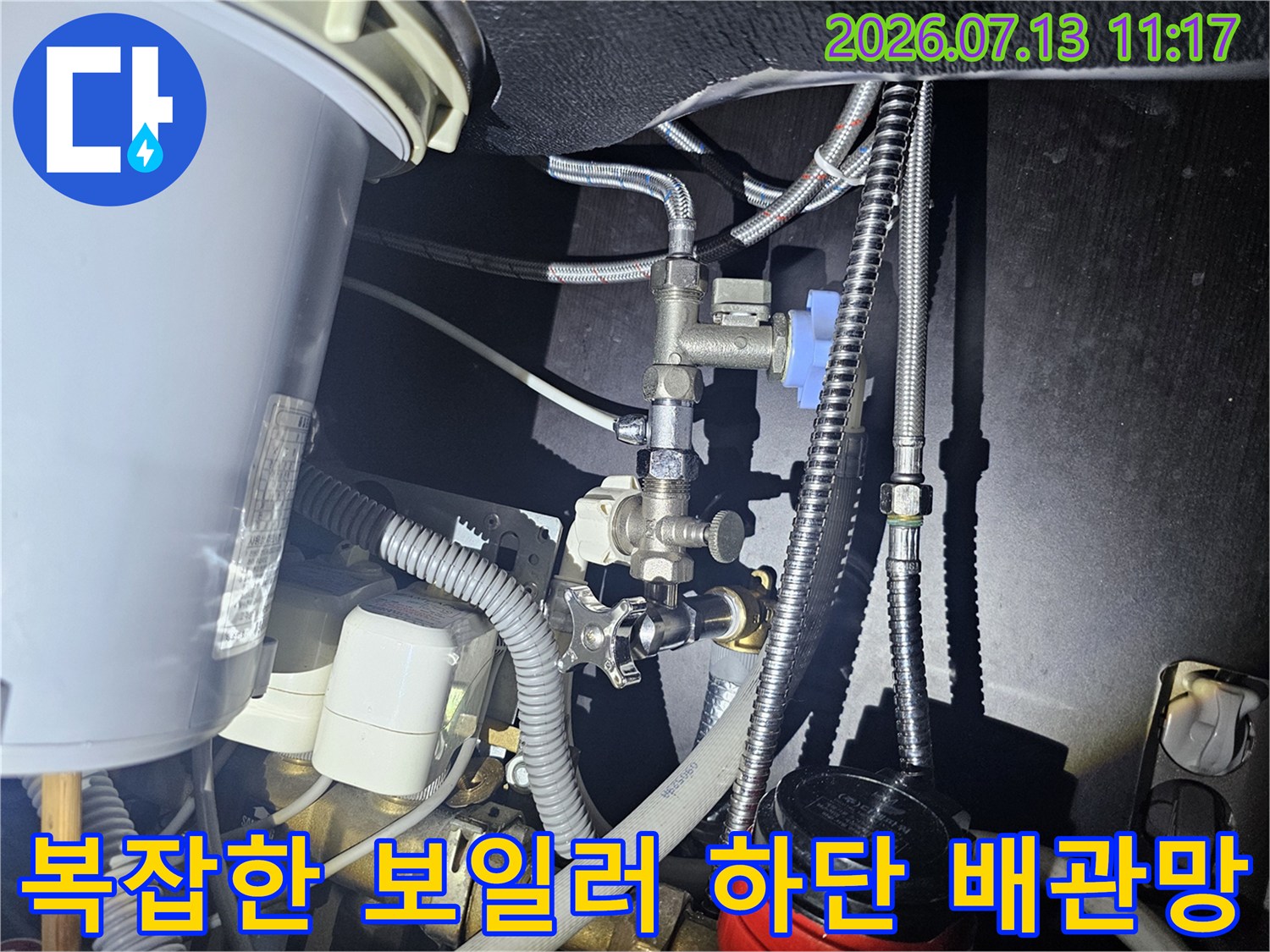 보일러 아래에 설치된 여러 갈래의 은색 금속 호스와 제어 밸브들의 모습