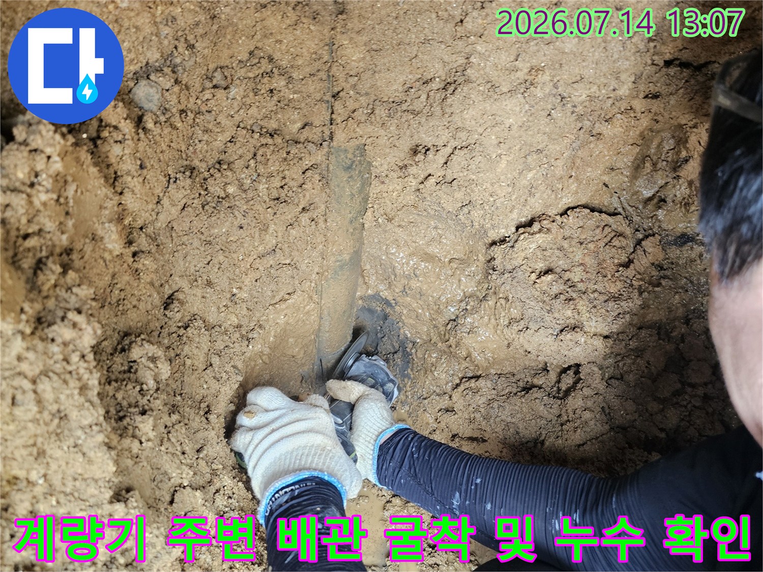 굴착된 토사 속에서 작업자가 계량기 연결 부위의 배관을 점검하는 모습
