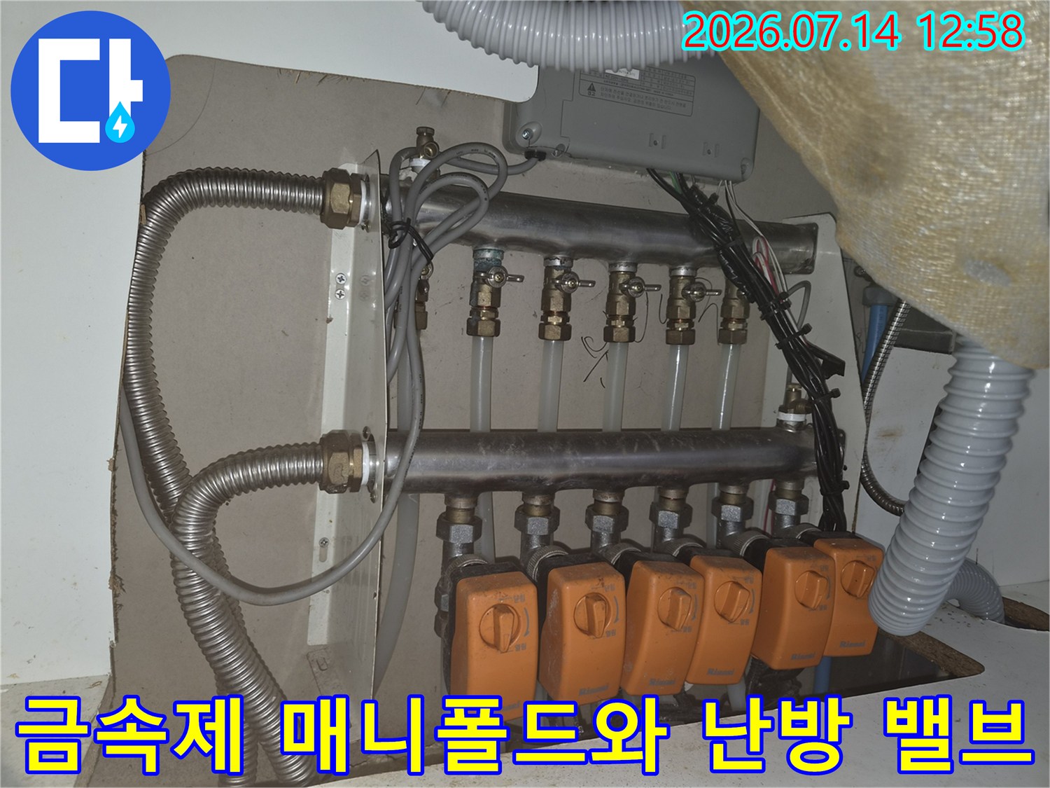 은색 금속관과 흰색 연결관 그리고 주황색 조절-밸브가 설치된 분배기
