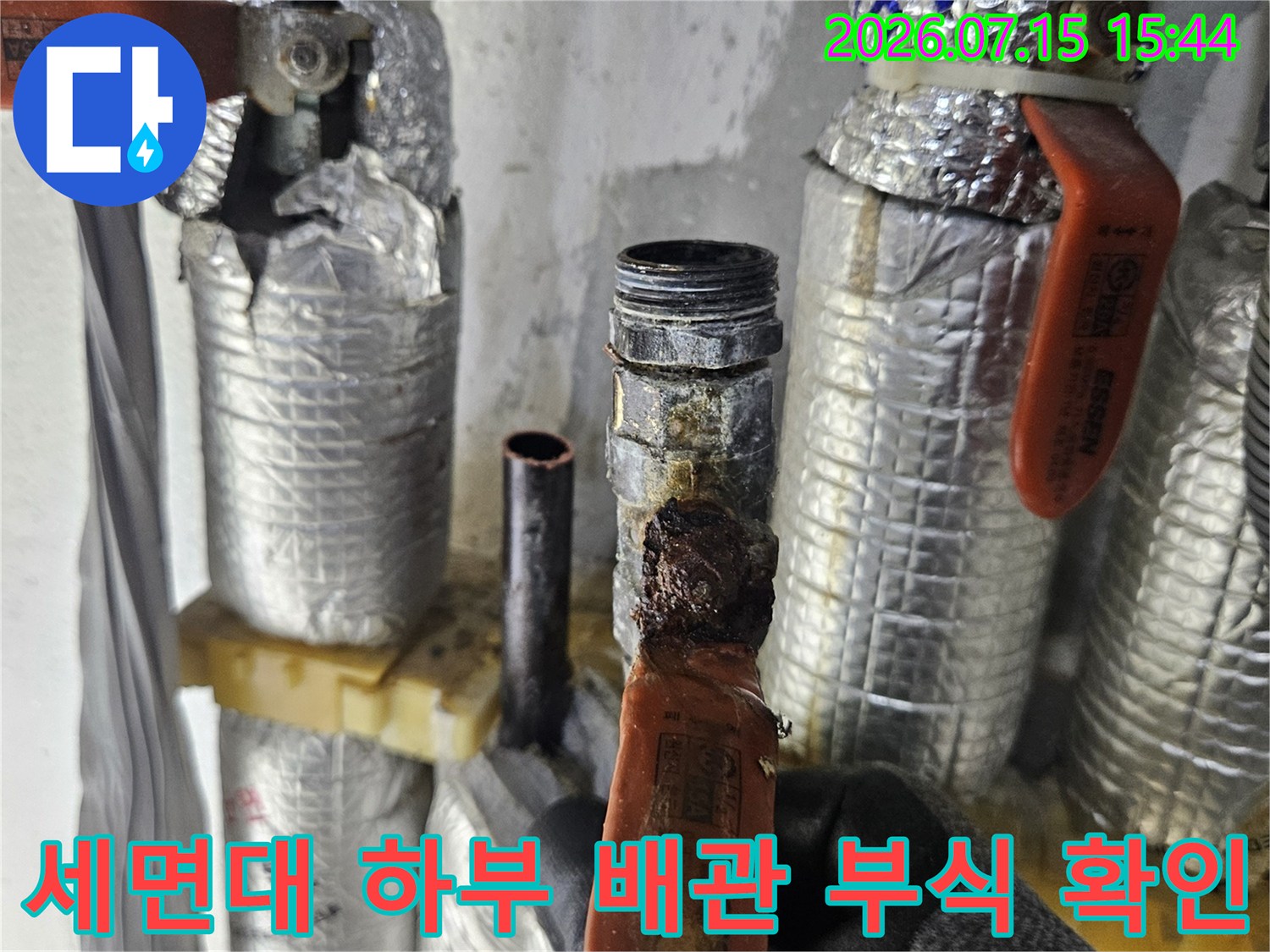 거친 질감의 노출된 배관 연결부가 누수로 인해 손상된 모습