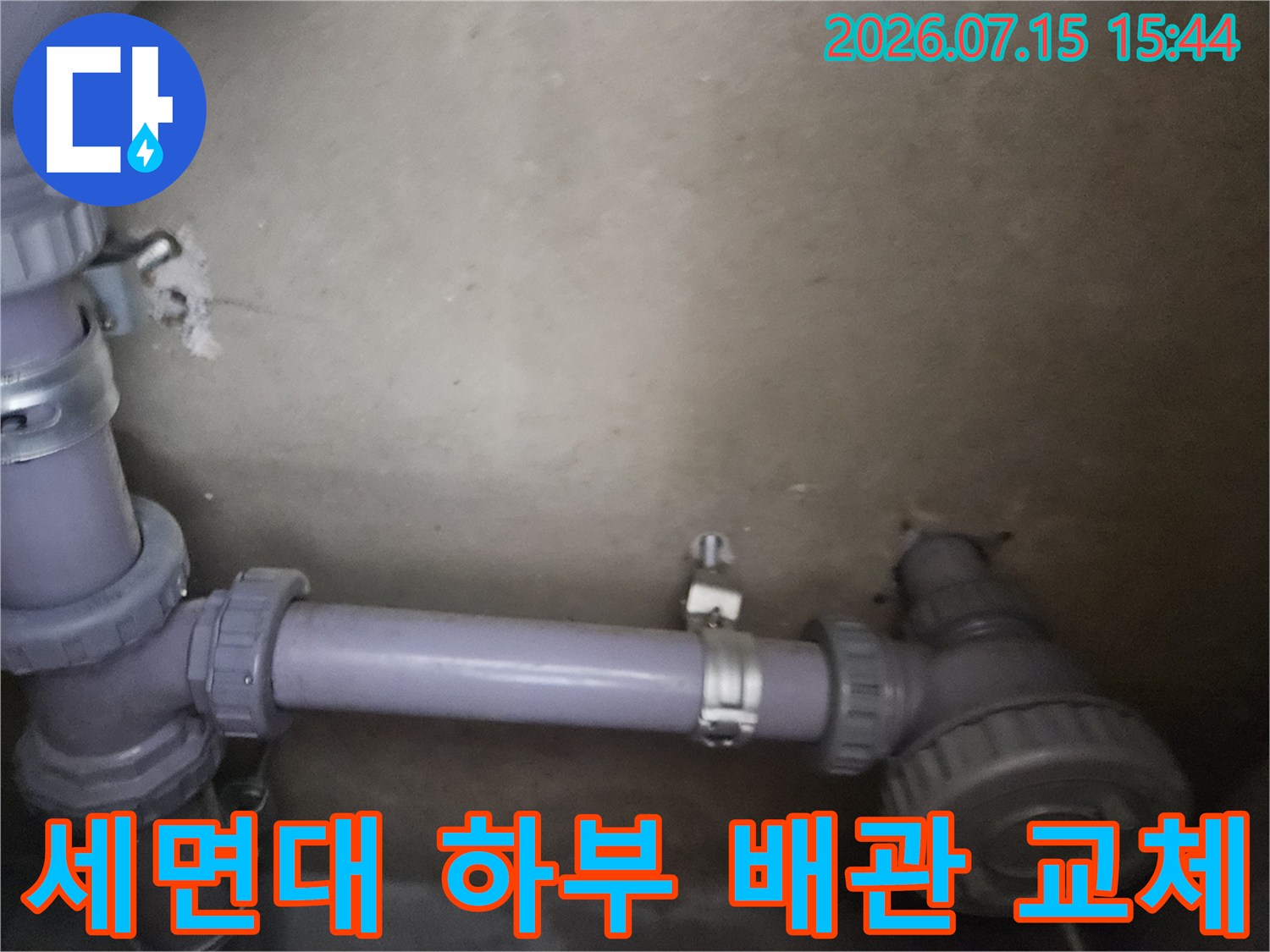 세면대 아래 위치한 보라색 배관과 연결 부속의 점검 모습
