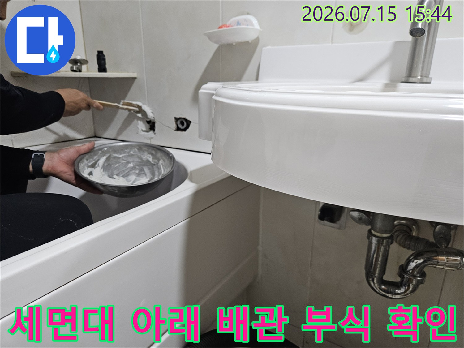 세면대 하단부의 노후된 배관 연결 지점을 손으로 직접 점검하는 모습