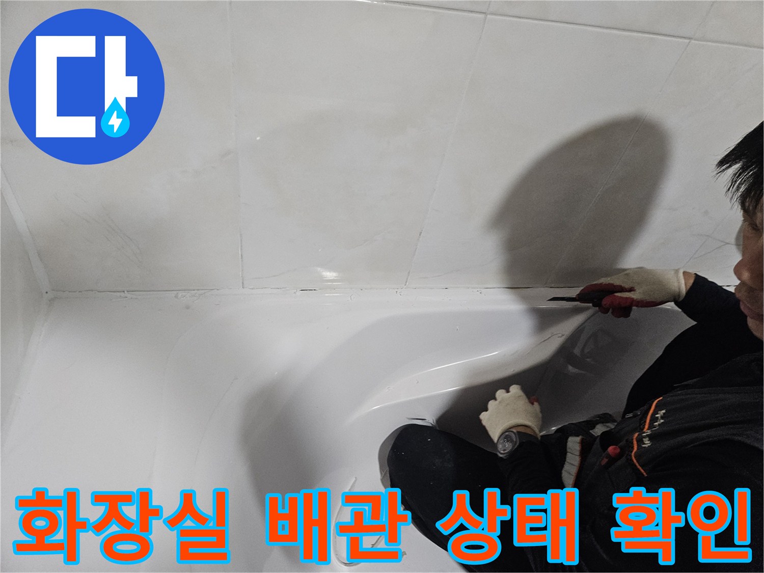 작업자가 장갑을 착용하고 욕조 하단 타일 틈새를 점검 중입니다