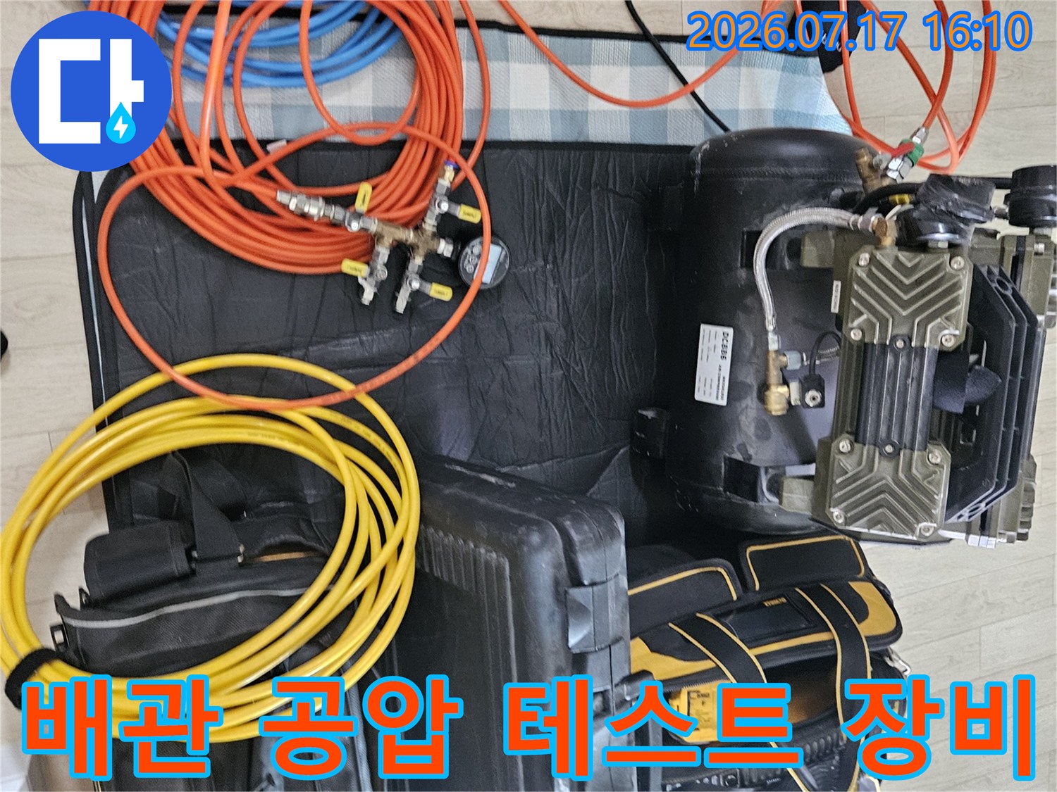 노란색과 주황색 호스가 연결된 배관 공압 측정기와 이동식 콤프레샤 세트