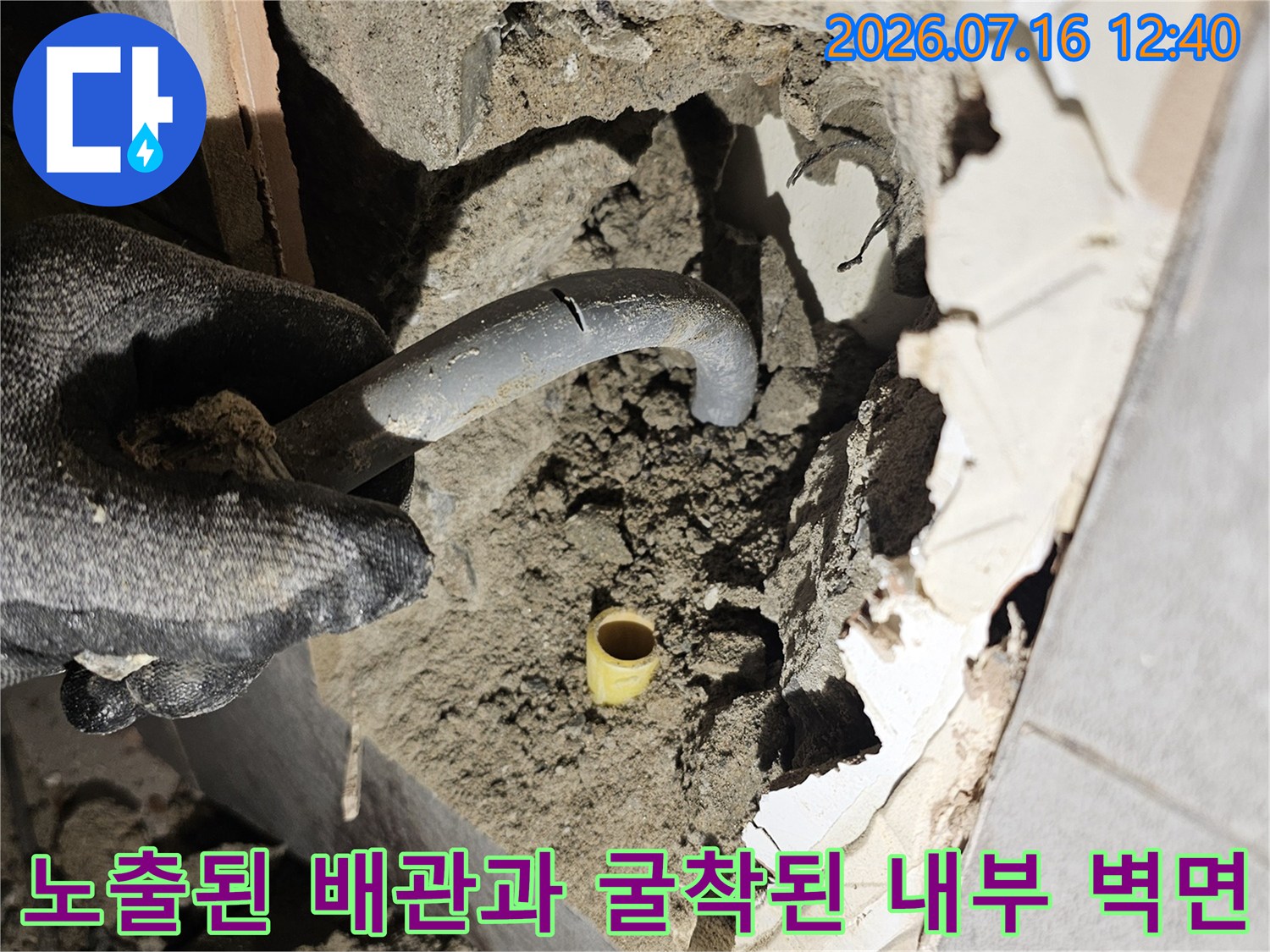 벽면을 파헤쳐 노출된 회색 배관과 주변 콘크리트 상태