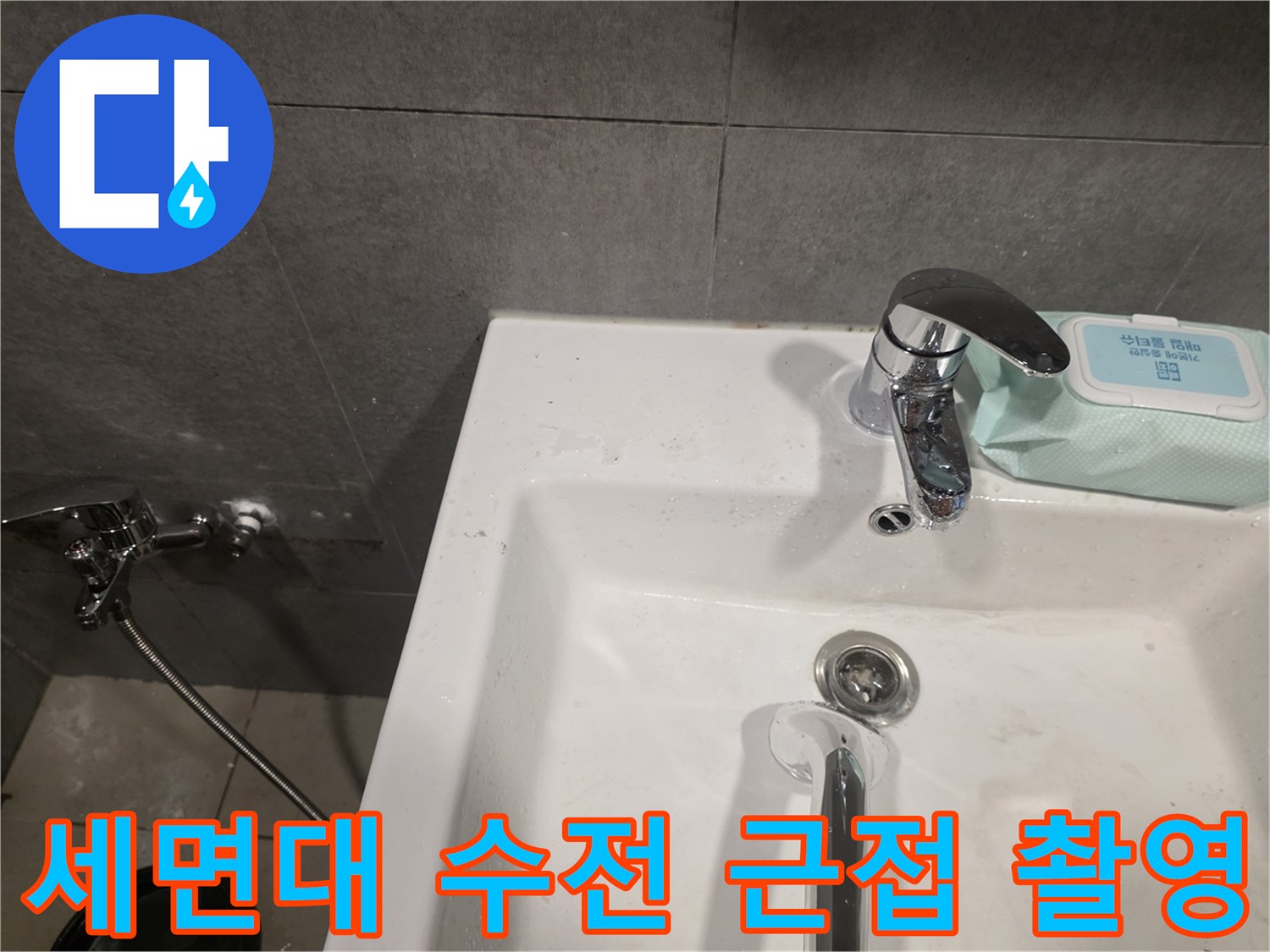 세면대 크롬 수전과 벽면 회색 타일의 접합 부위