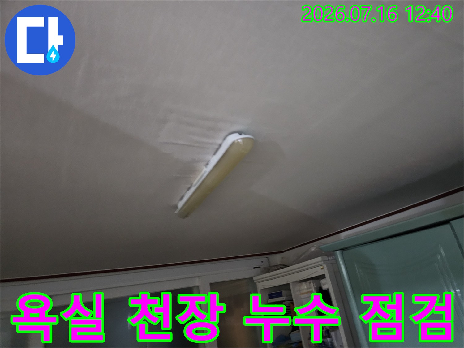 천장에 설치된 형광등 주변의 습기 흔적과 마감재 상태를 점검하는 모습