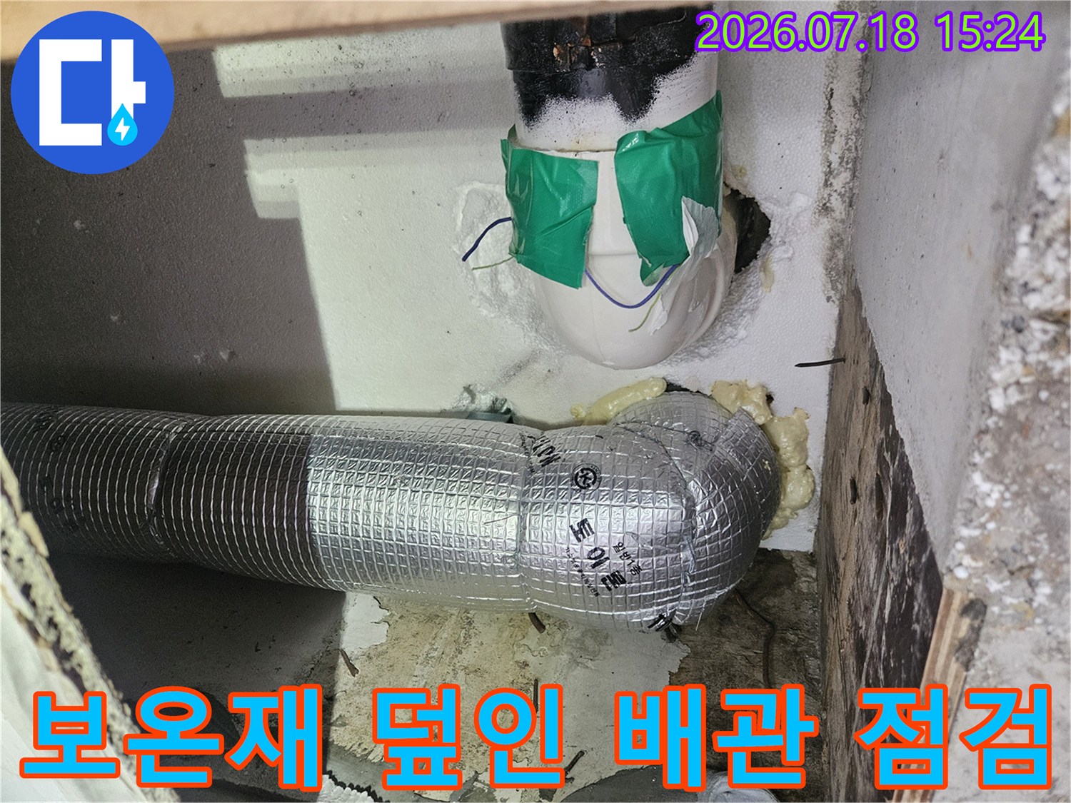 반사성 보온재로 감싸진 수직 하수 배관과 연결부 상세 촬영