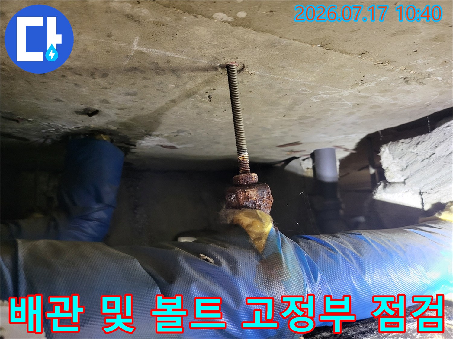 천장 안쪽 배관과 전산볼트가 연결된 부분을 정밀하게 검사하는 엔지니어의 작업 모습