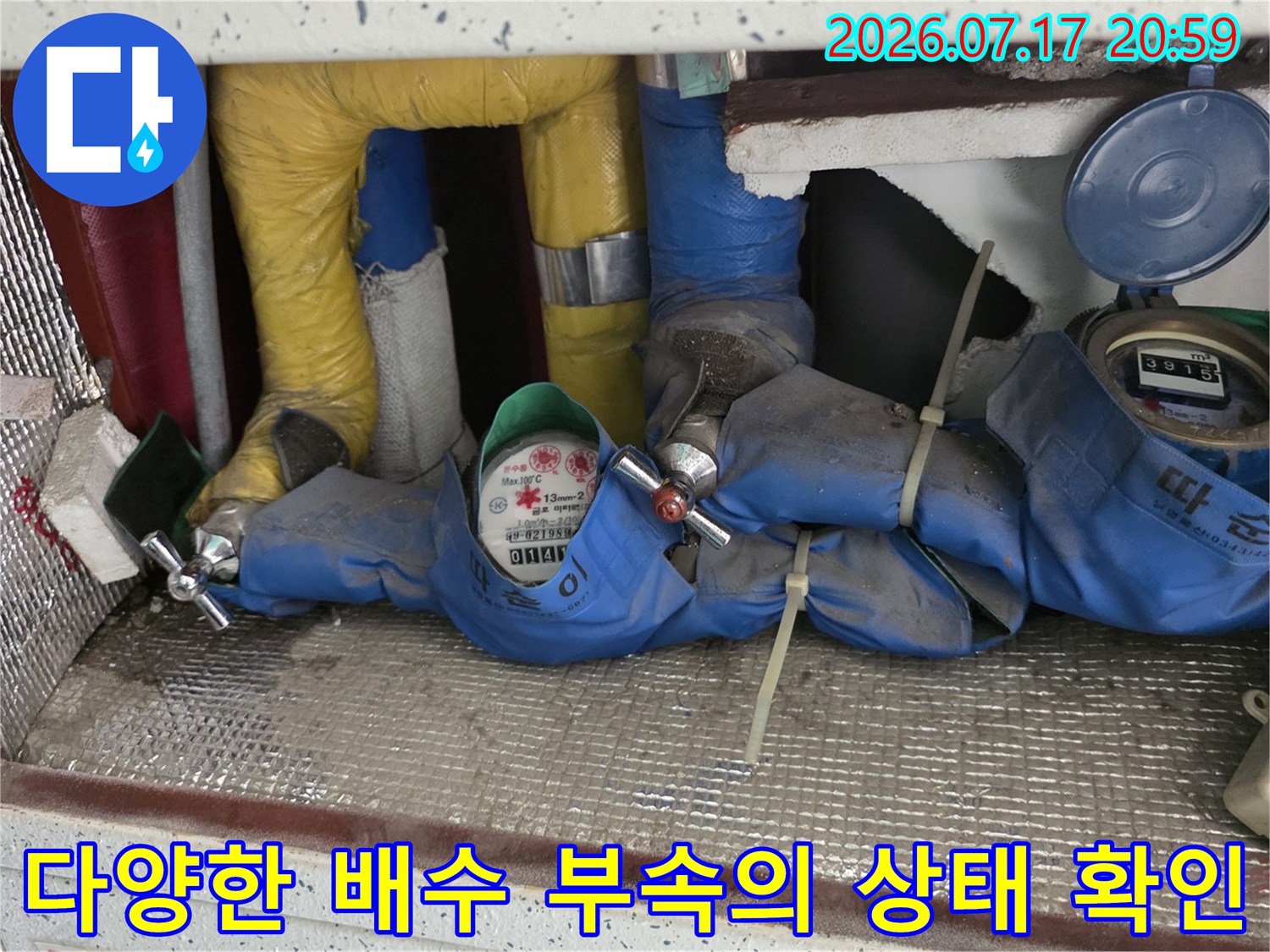 싱크대 주변에 배치된 여러 종류의 배수 관련 자재와 연결부를 점검하는 모습입니다.