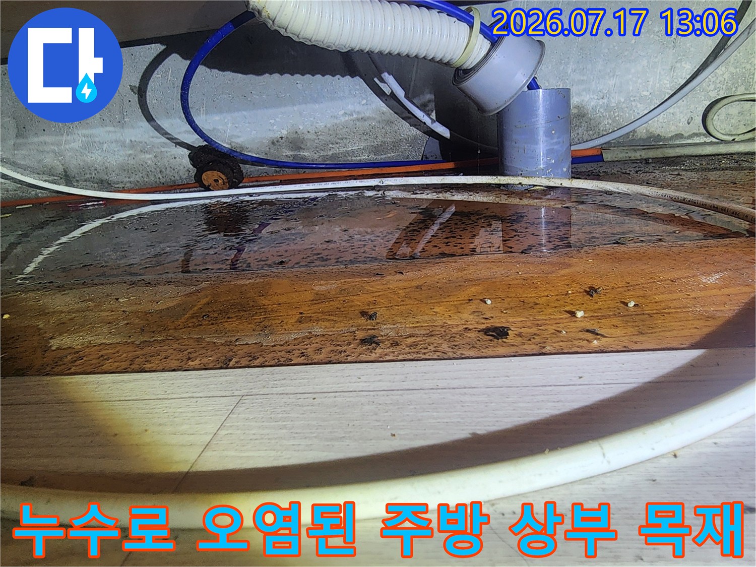 천장 배관 주변의 나무 자재가 물에 젖어 짙은 갈색 얼룩이 형성된 상태