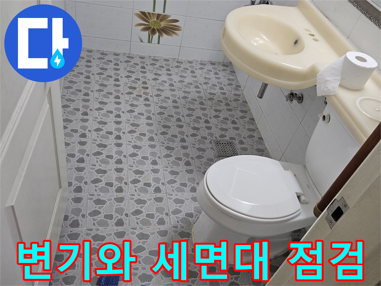 화장실 내부에 설치된 양변기와 세면대의 연결 부위를 촬영한 사진입니다.