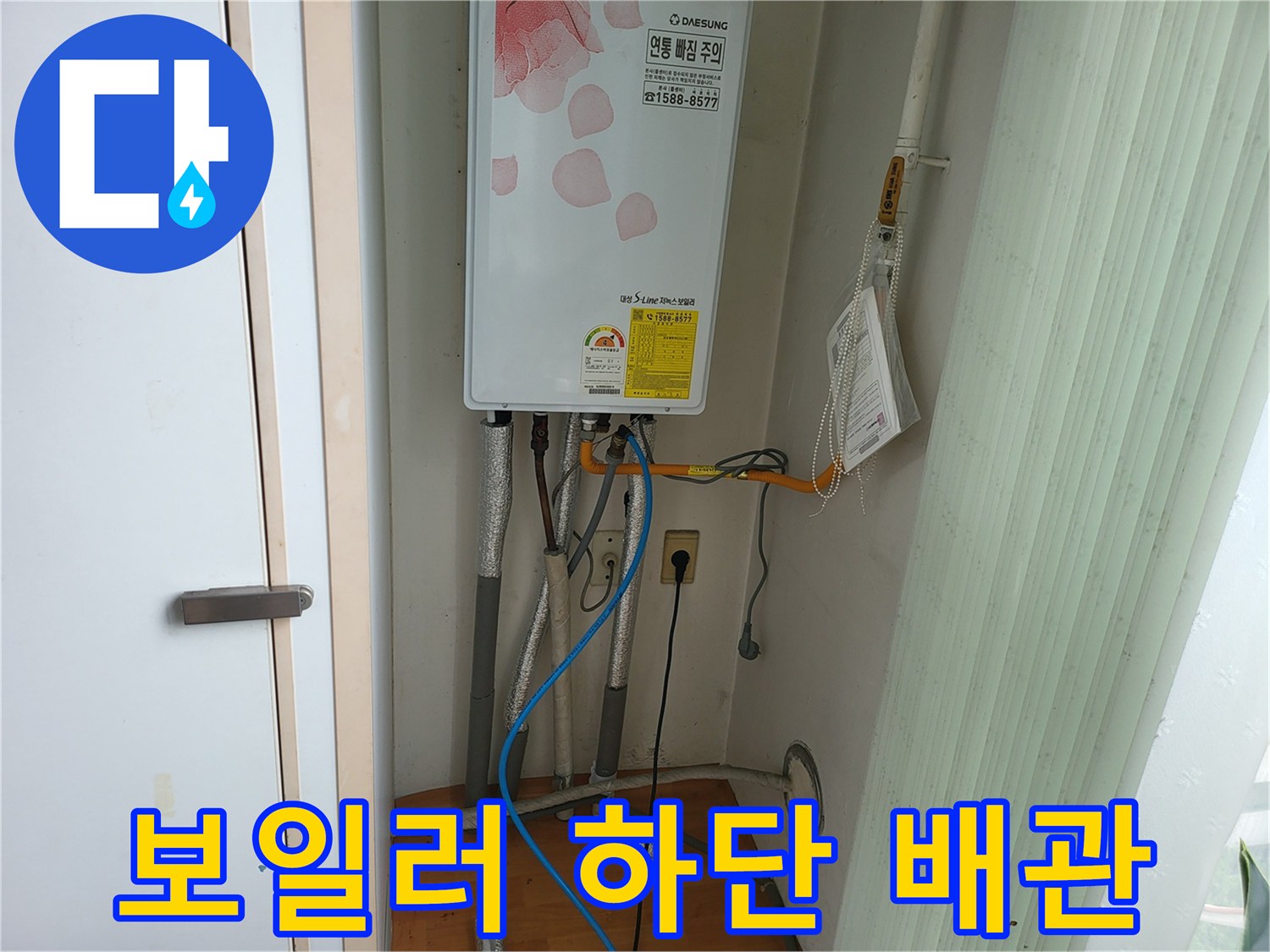 보일러 아래에 설치된 노란색 온수 배관과 급수 연결관