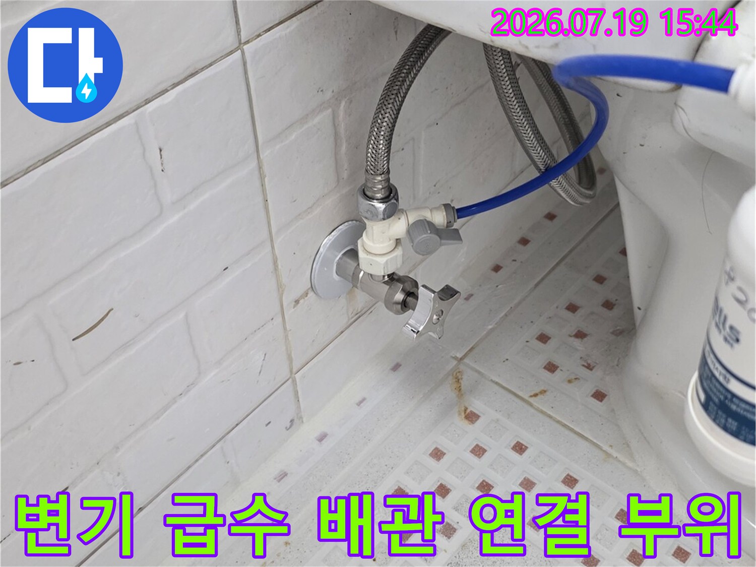화장실 변기 뒤편의 급수 밸브와 파란색 고압 호스가 연결된 모습