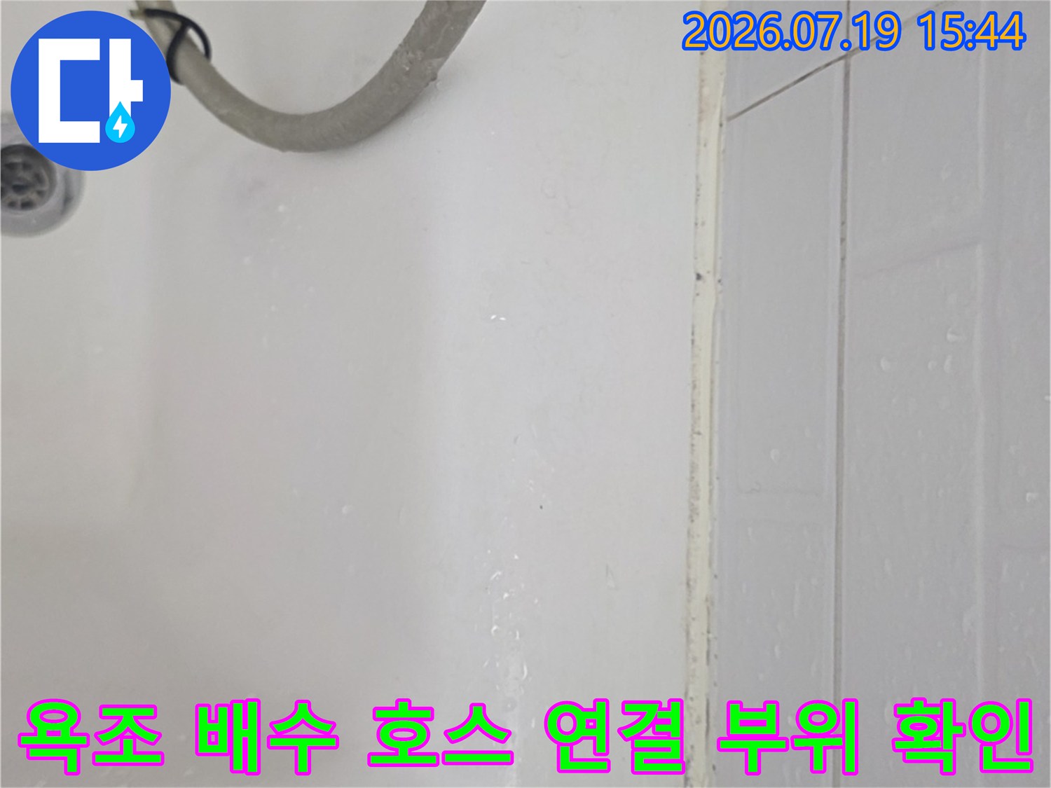 흰색 욕조의 배수구와 연결된 회색 호스가 놓여 있는 모습-누수 점검 사진
