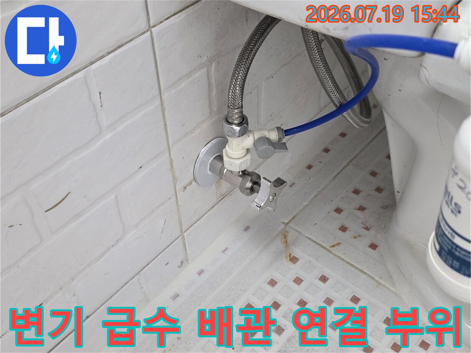 흰색 타일 벽면에 설치된 변기 급수 밸브와 파란색 고압 호스-연결 상태 점검