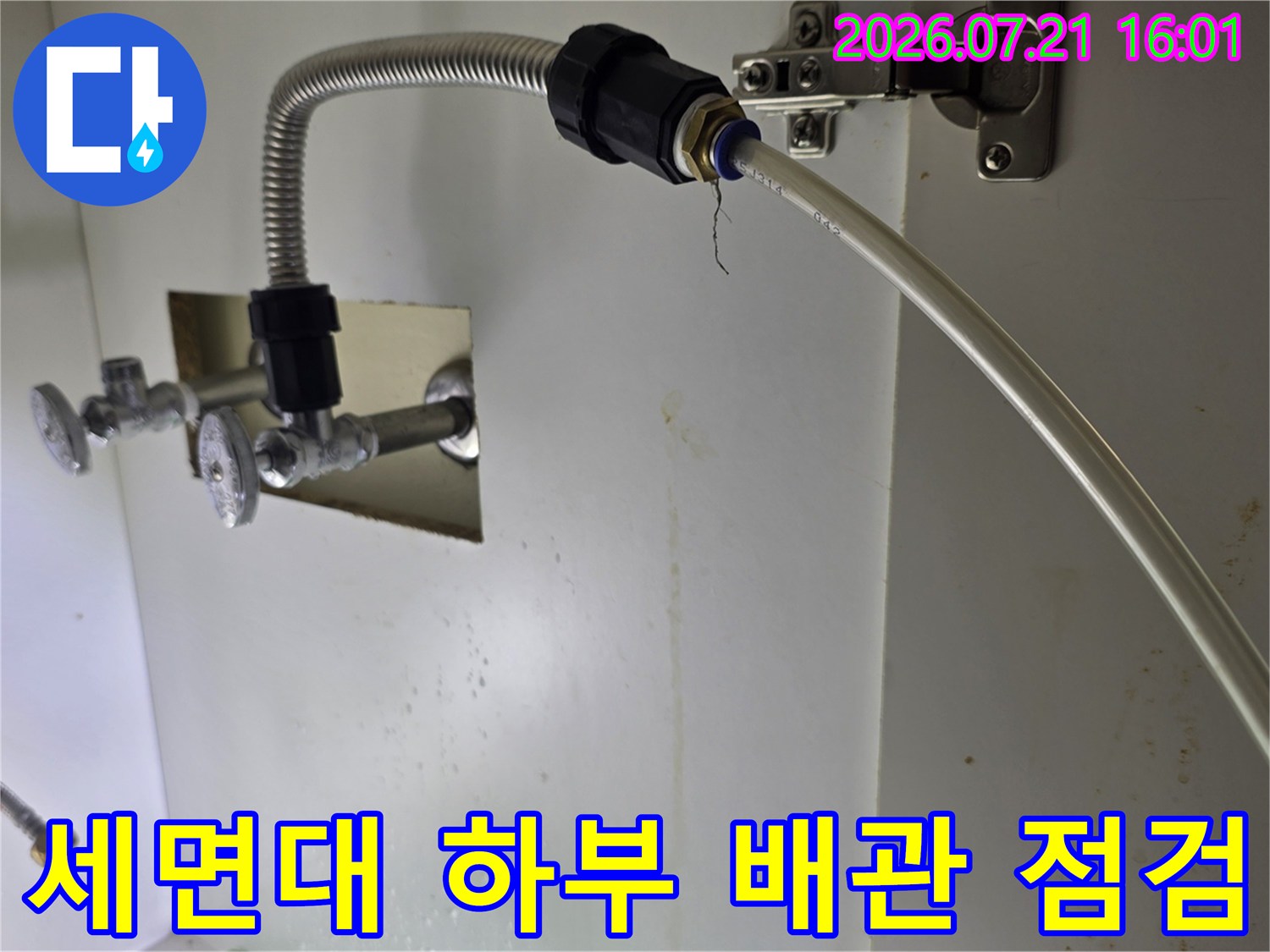 세면대 아래쪽으로 연결된 은색 자바라 호스와 노출된 배관 부위 점검 장면