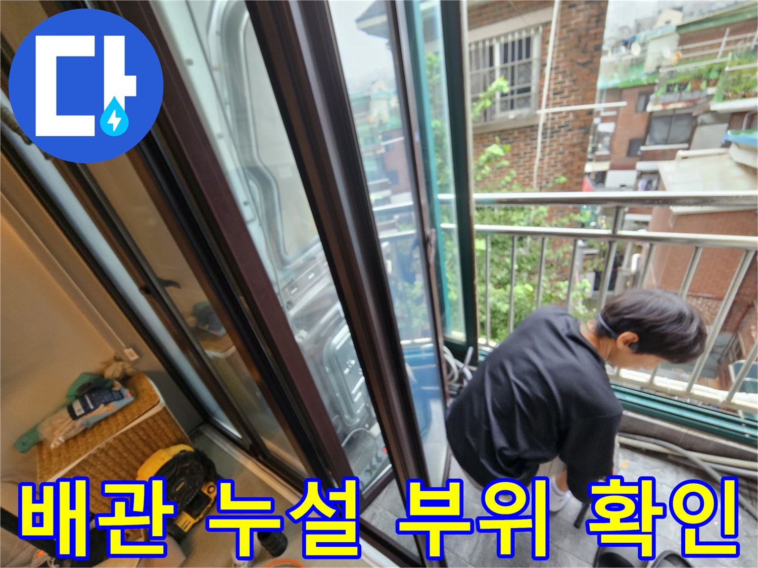 난간 너머 외벽 쪽 배관 상태를 면밀히 조사하는 작업자