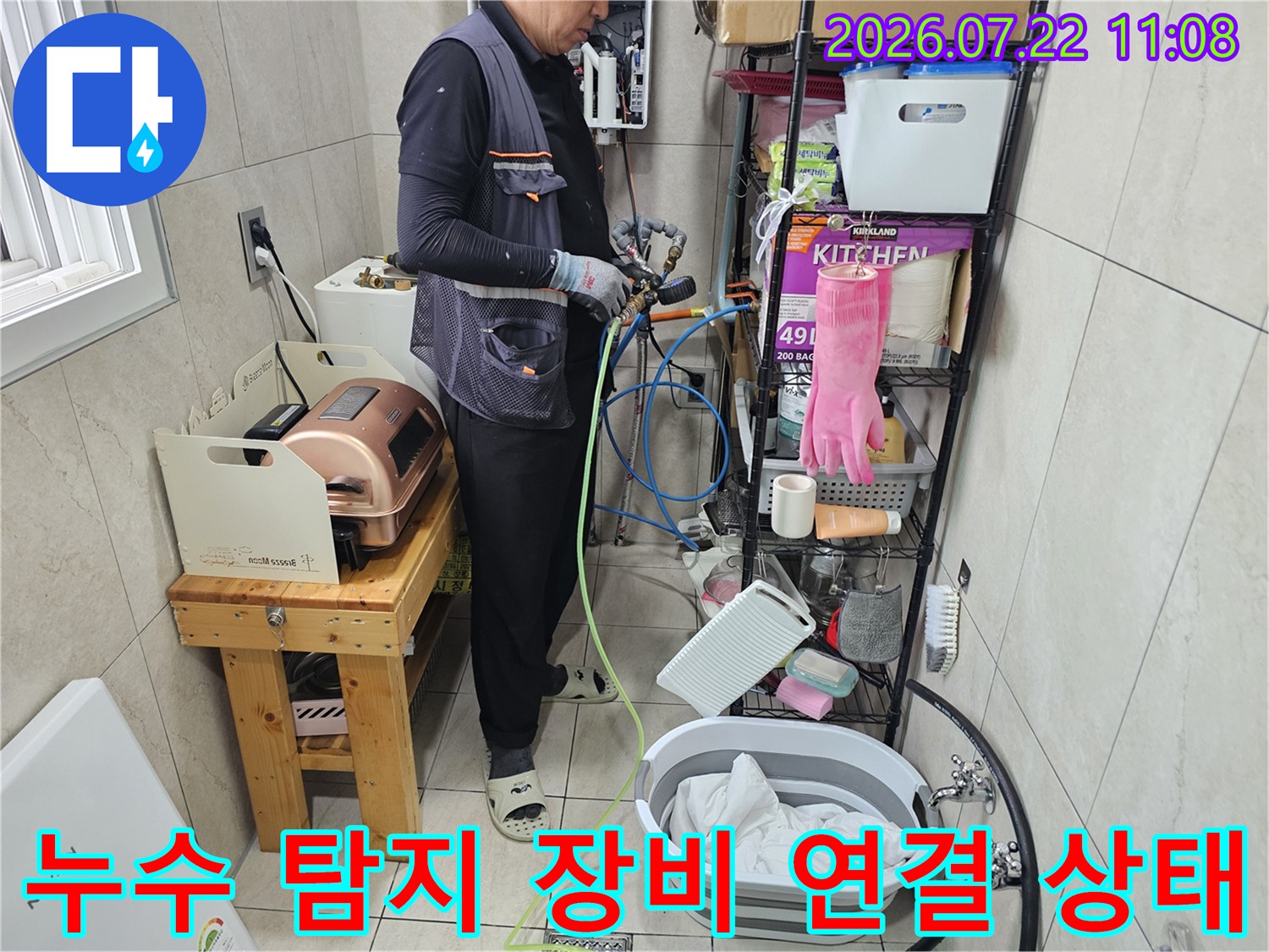 엔지니어가 다용도실 배관에 파란색과 노란색 호스를 연결하여 누수 테스트를 진행하는 모습