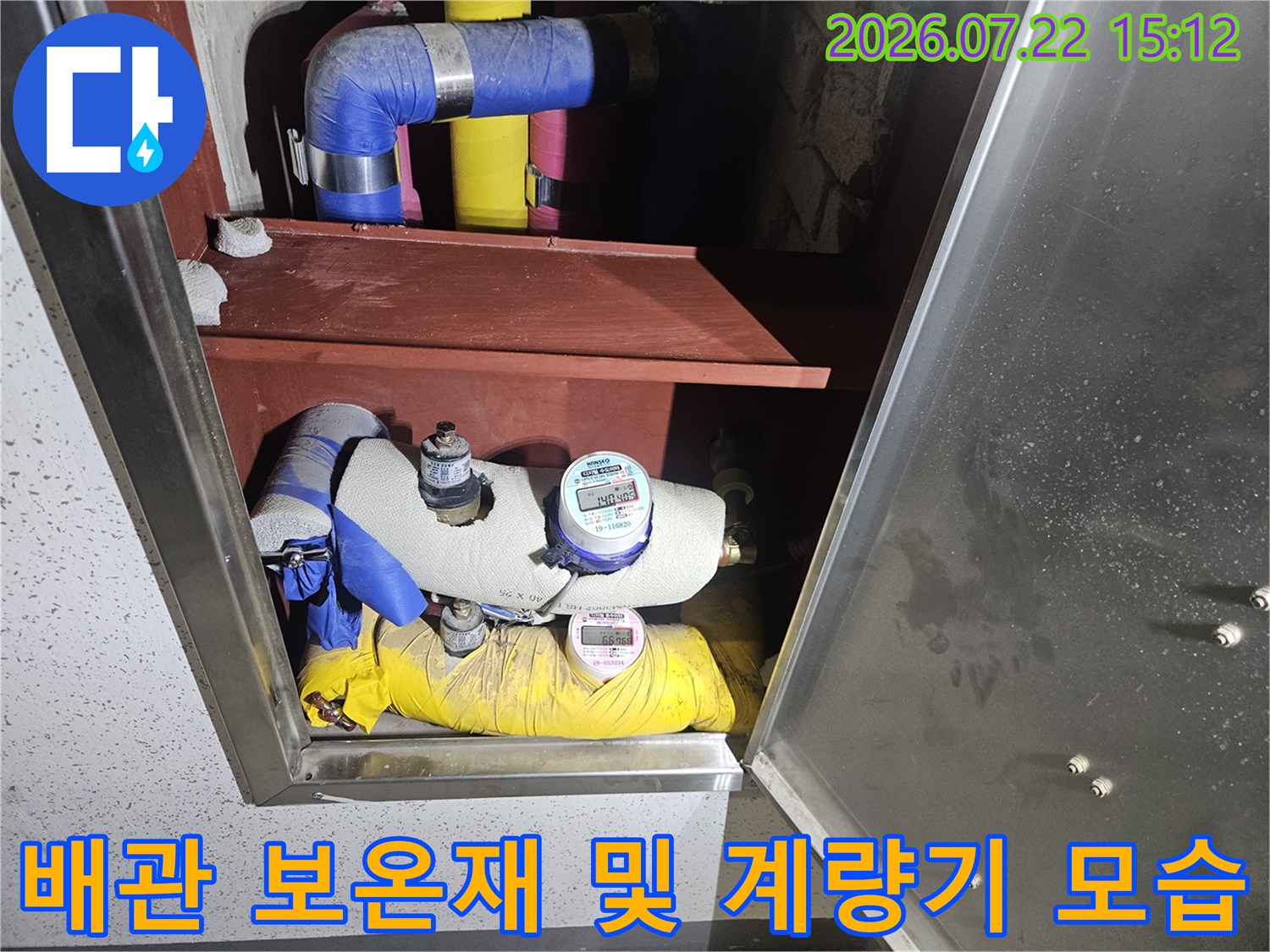 금속제 함 내부에 설치된 노란색과 파란색 단열재 처리된 수도 배관의 상세 사진