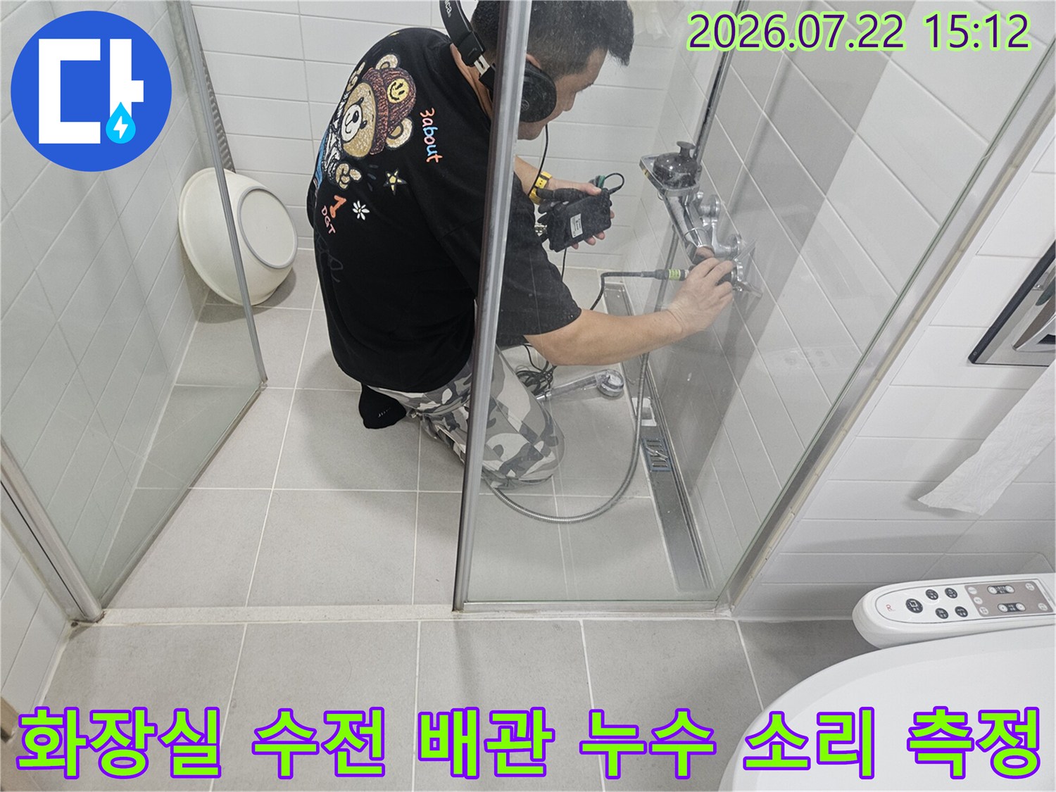 엔지니어가 화장실 샤워기 밸브 부분에 탐지 센서를 대고 헤드셋으로 소리를 확인하는 사진