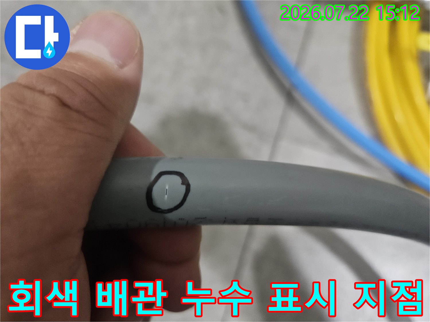 회색빛의 수도 배관 표면에 검은색 펜으로 누수 의심 지점을 동그랗게 표시한 모습