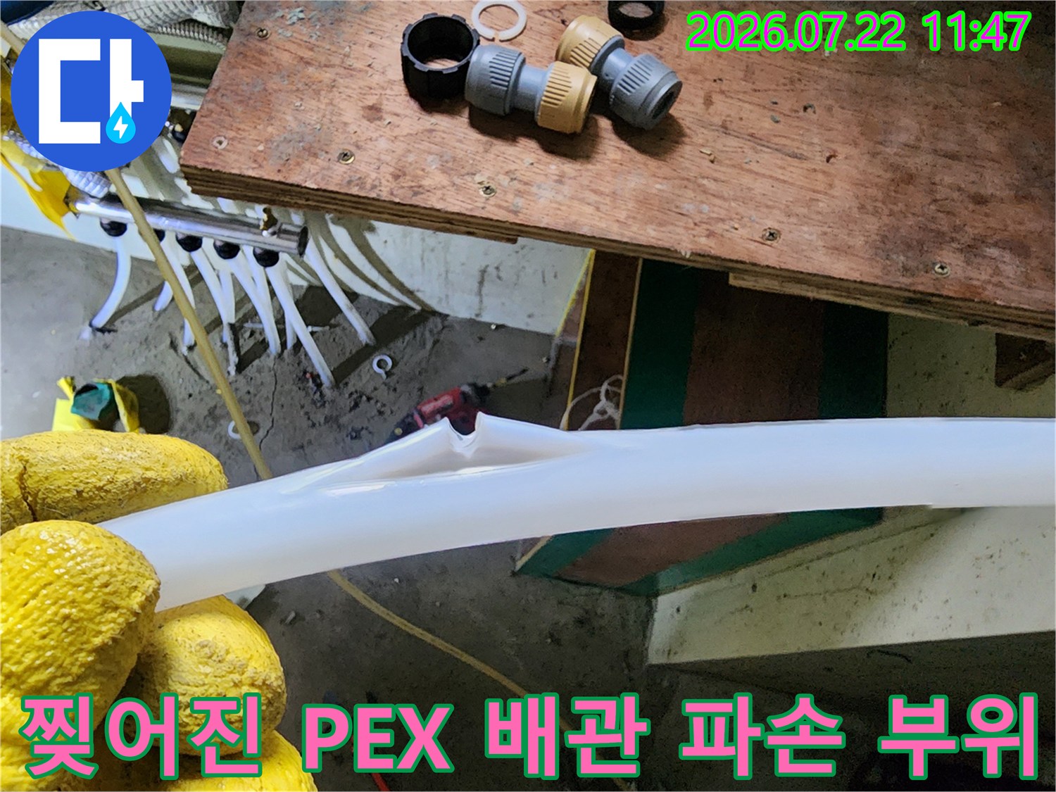 노란 장갑을 착용한 작업자가 찢어진 흰색 배관의 단면을 보여주고 있는 근접 사진