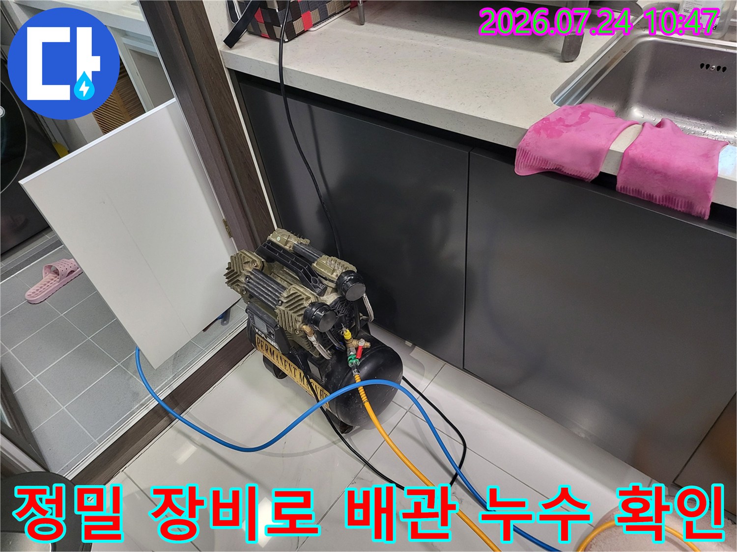 싱크대 하부 공간에서 공압 테스트 호스를 연결하여 배관 상태를 점검하는 장면